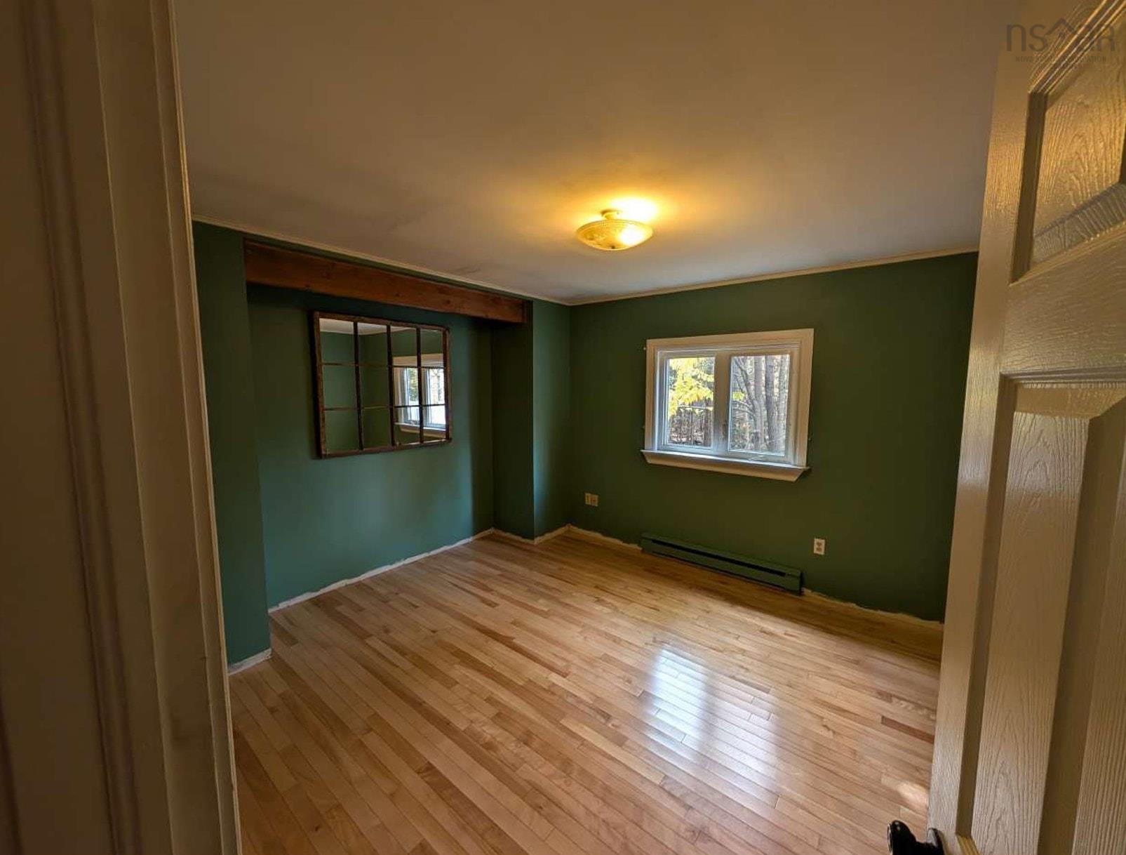 19 Foster Avenue, Fall River, NS (MLS® 202625937) — Room featuring wood-finish flooring, a wall-mounted paneled mirror, and a window with white trim