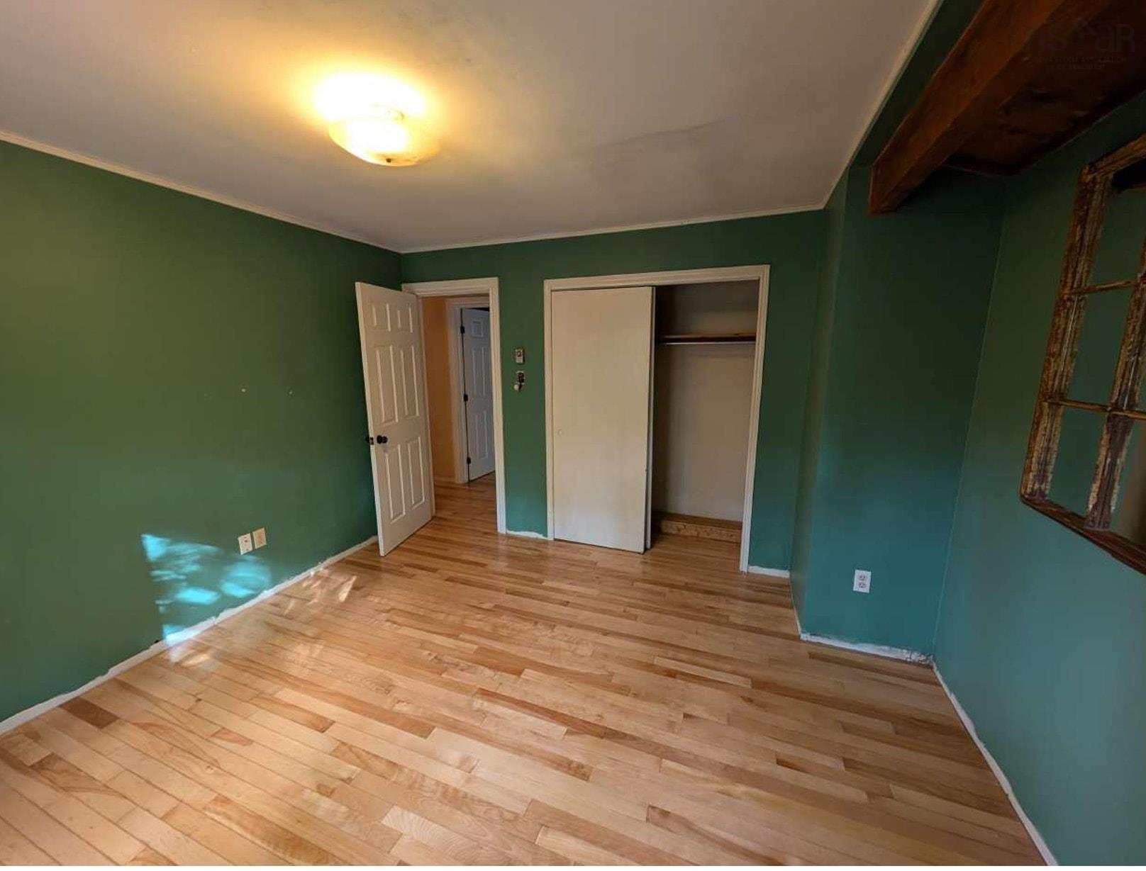 19 Foster Avenue, Fall River, NS (MLS® 202625937) — Wood-finish flooring, recessed closet with sliding doors, six-panel interior door, and exposed timber ceiling accent