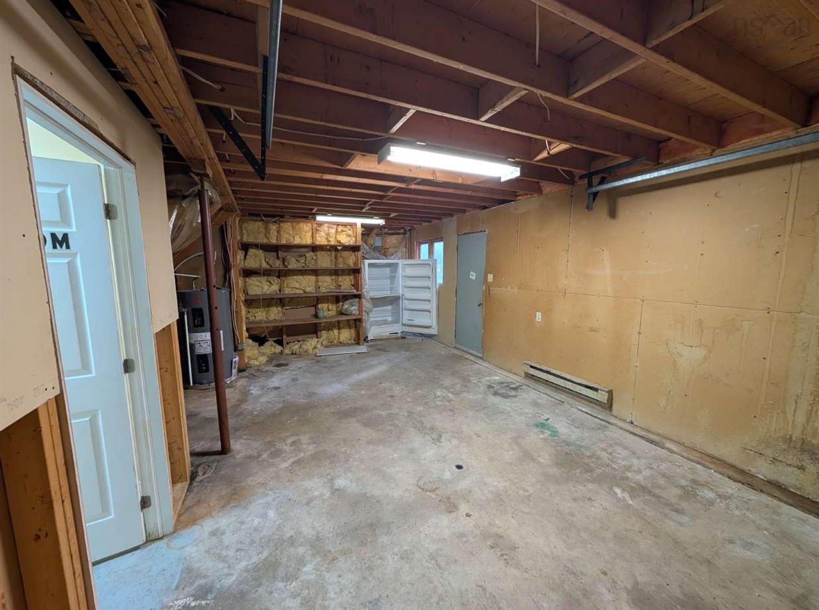 19 Foster Avenue, Fall River, NS (MLS® 202625937) — Utility space featuring exposed timber ceiling joists, concrete flooring, integrated wall shelving, and dual overhead fluorescent lighting fixtures