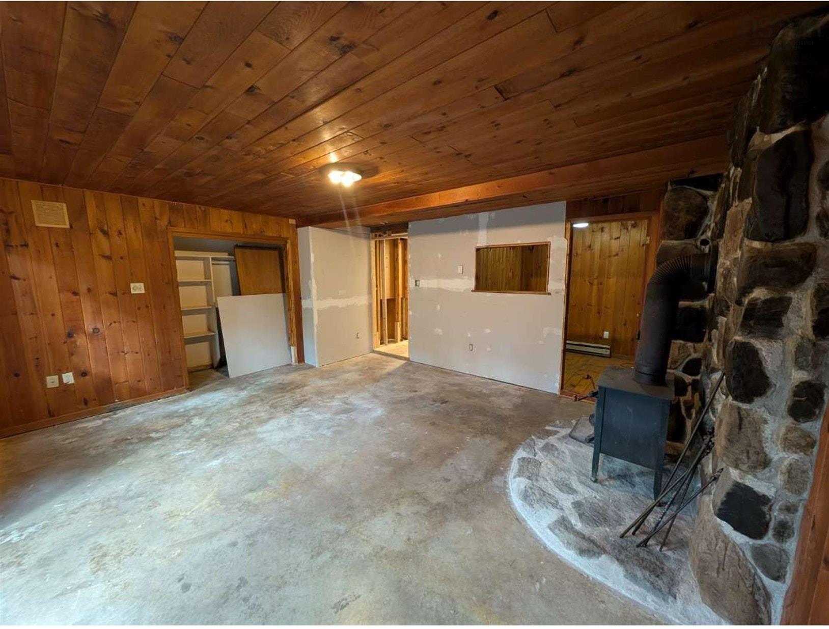 19 Foster Avenue, Fall River, NS (MLS® 202625937) — Interior space featuring wood-plank ceilings and walls, a natural stone fireplace surround with a stone hearth, and a wood-burning stove