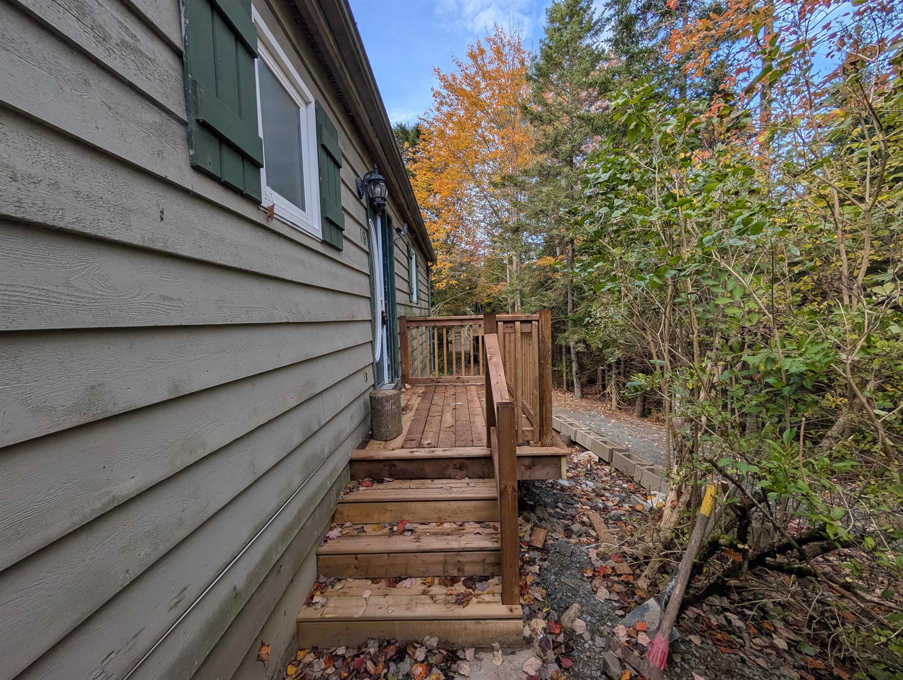 19 Foster Avenue, Fall River, NS (MLS® 202625937) — Horizontal lap siding exterior featuring green shutters, a wood deck with railings, and matching wood stairs