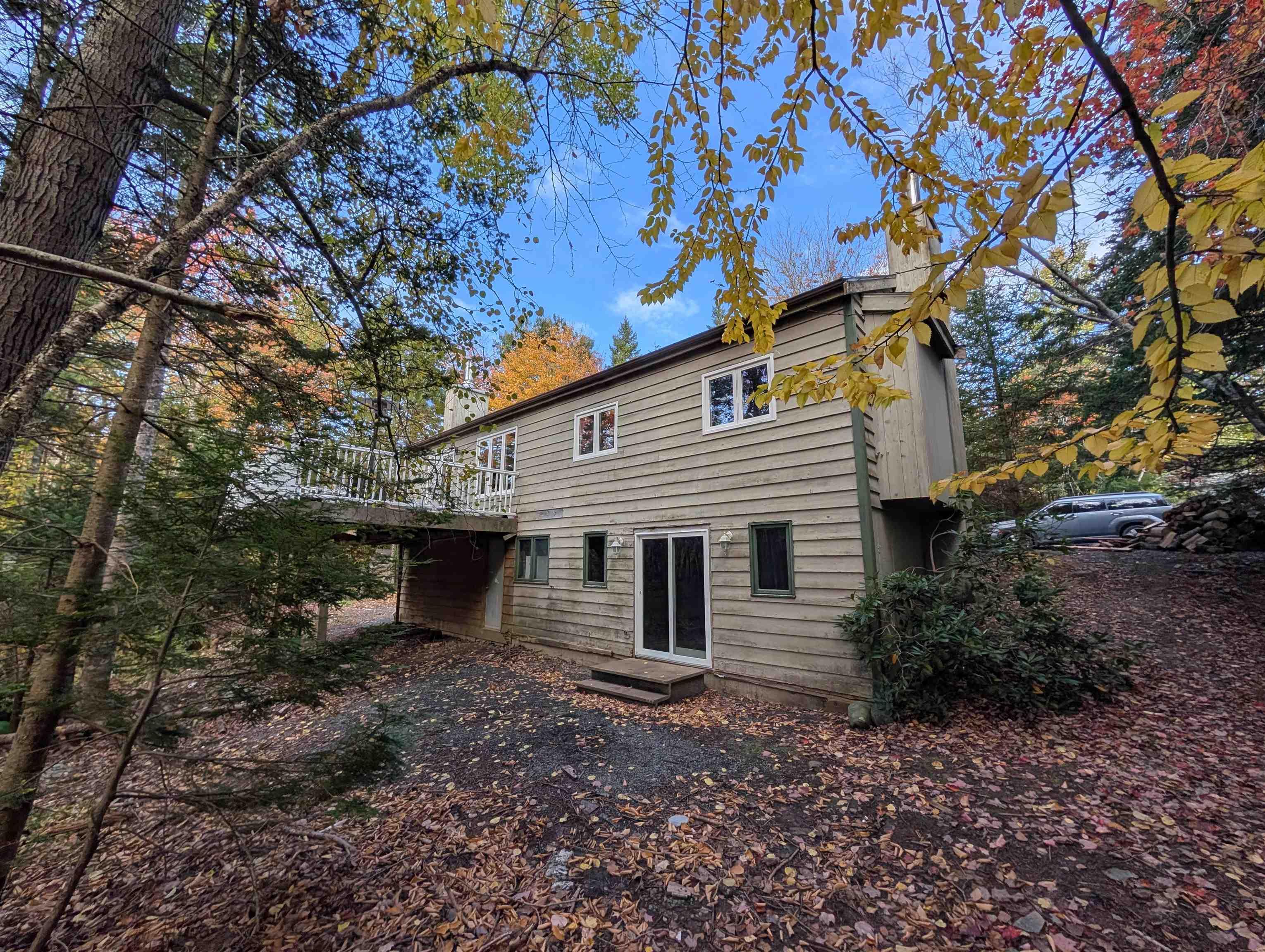 19 Foster Avenue, Fall River, NS (MLS® 202625937) — Two-story wood-sided exterior featuring an elevated deck, sliding glass doors, and mature woodland surroundings