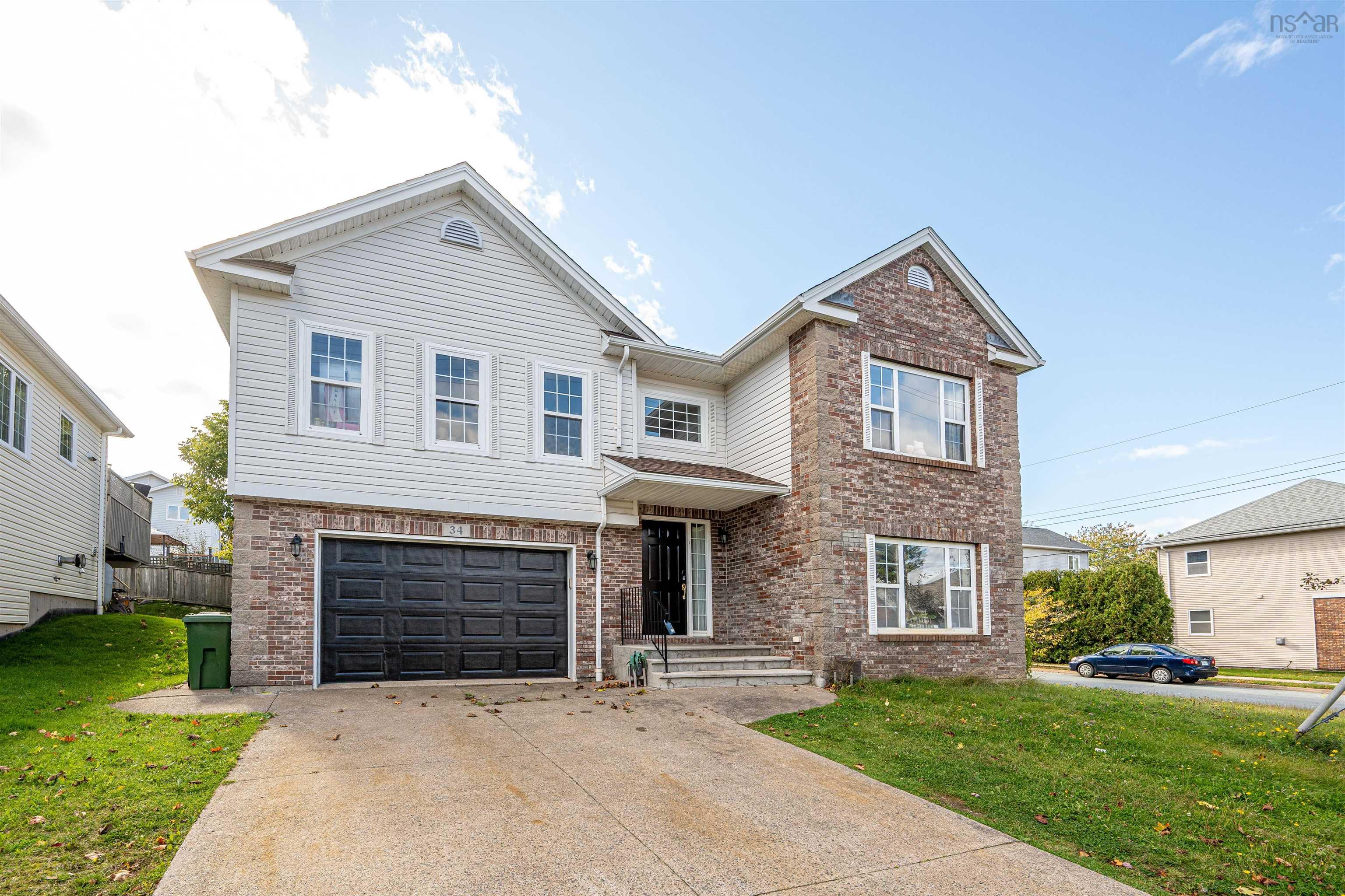 34 Lancaster Drive, Clayton Park, NS (MLS® 202626151) — Two-story exterior featuring a mix of stone veneer and horizontal siding, an attached two-car garage, multi-pane windows, and a concrete driveway