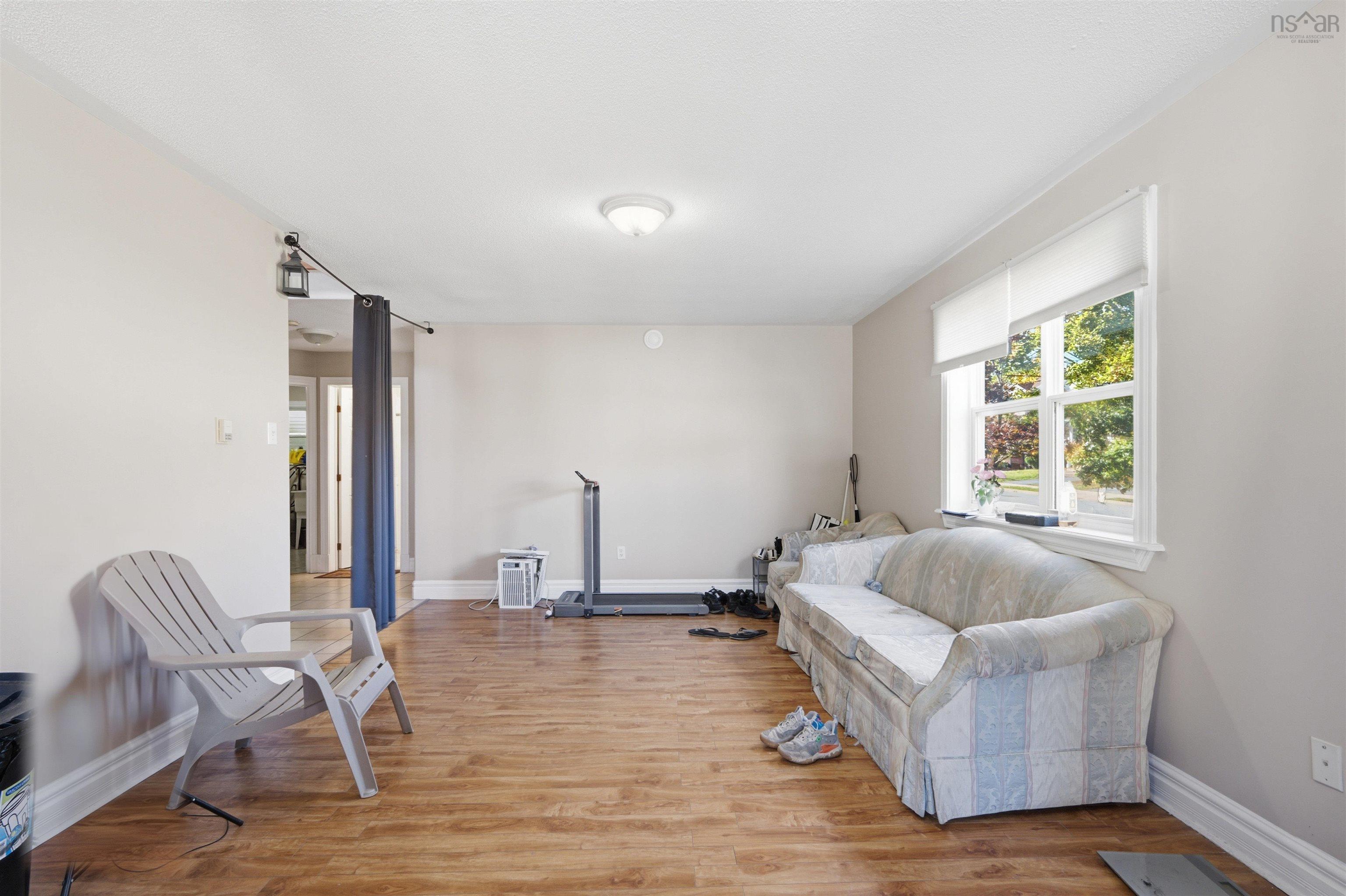34 Lancaster Drive, Clayton Park, NS (MLS® 202626151) — Living space featuring wood-finish flooring, a large window with roller shades, and a ceiling-mounted light fixture