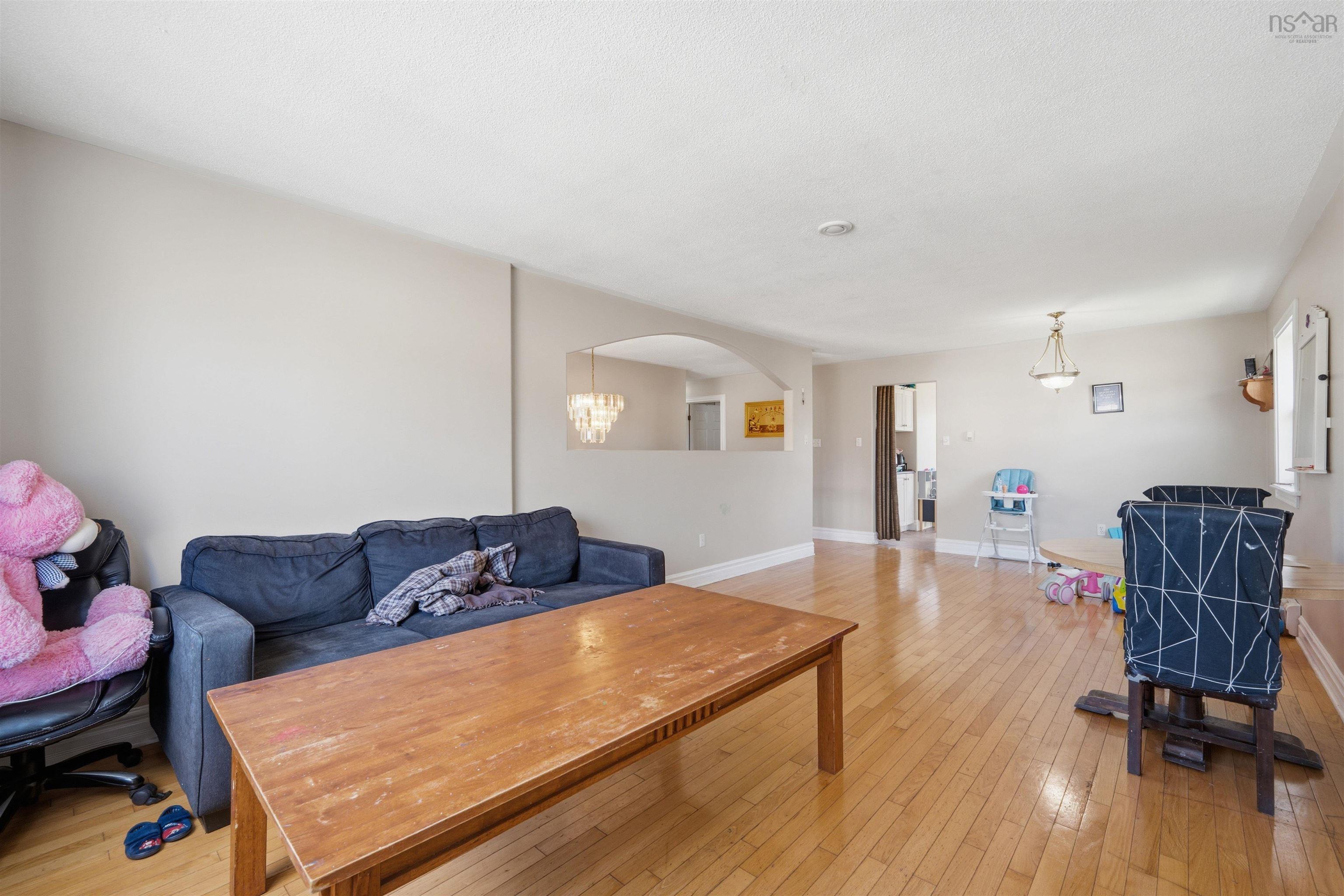 34 Lancaster Drive, Clayton Park, NS (MLS® 202626151) — Open-concept interior featuring light-toned wood-finish flooring, a decorative arched wall cutout, and two ceiling-mounted light fixtures