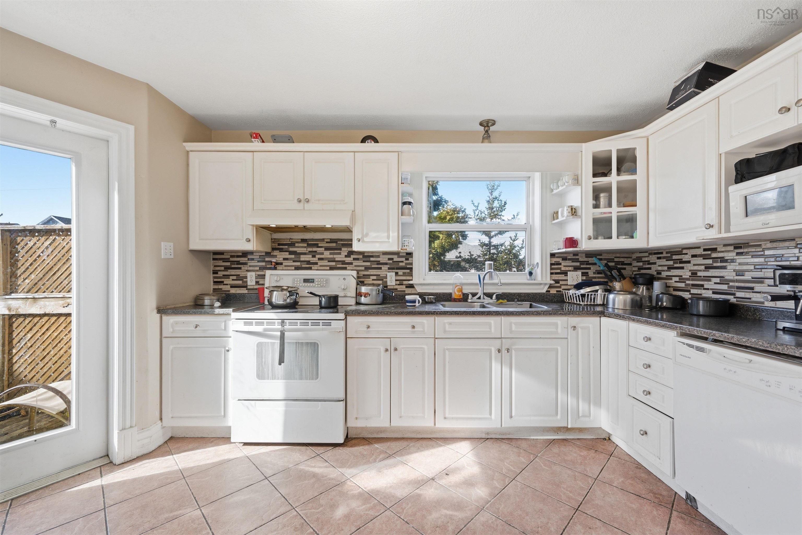 34 Lancaster Drive, Clayton Park, NS (MLS® 202626151) — Kitchen featuring white shaker-style cabinetry, a multi-tone tile backsplash, tiled flooring, and a glass-paned exterior door
