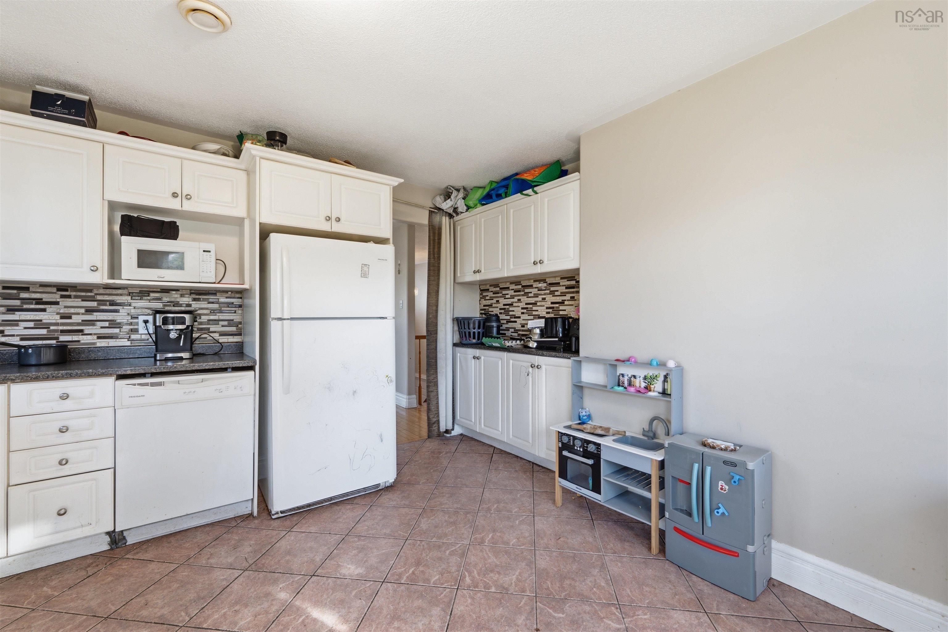 34 Lancaster Drive, Clayton Park, NS (MLS® 202626151) — Kitchen featuring white Shaker-style cabinetry, multi-tonal stacked stone backsplash, dark stone-finish countertops, and ceramic tile flooring