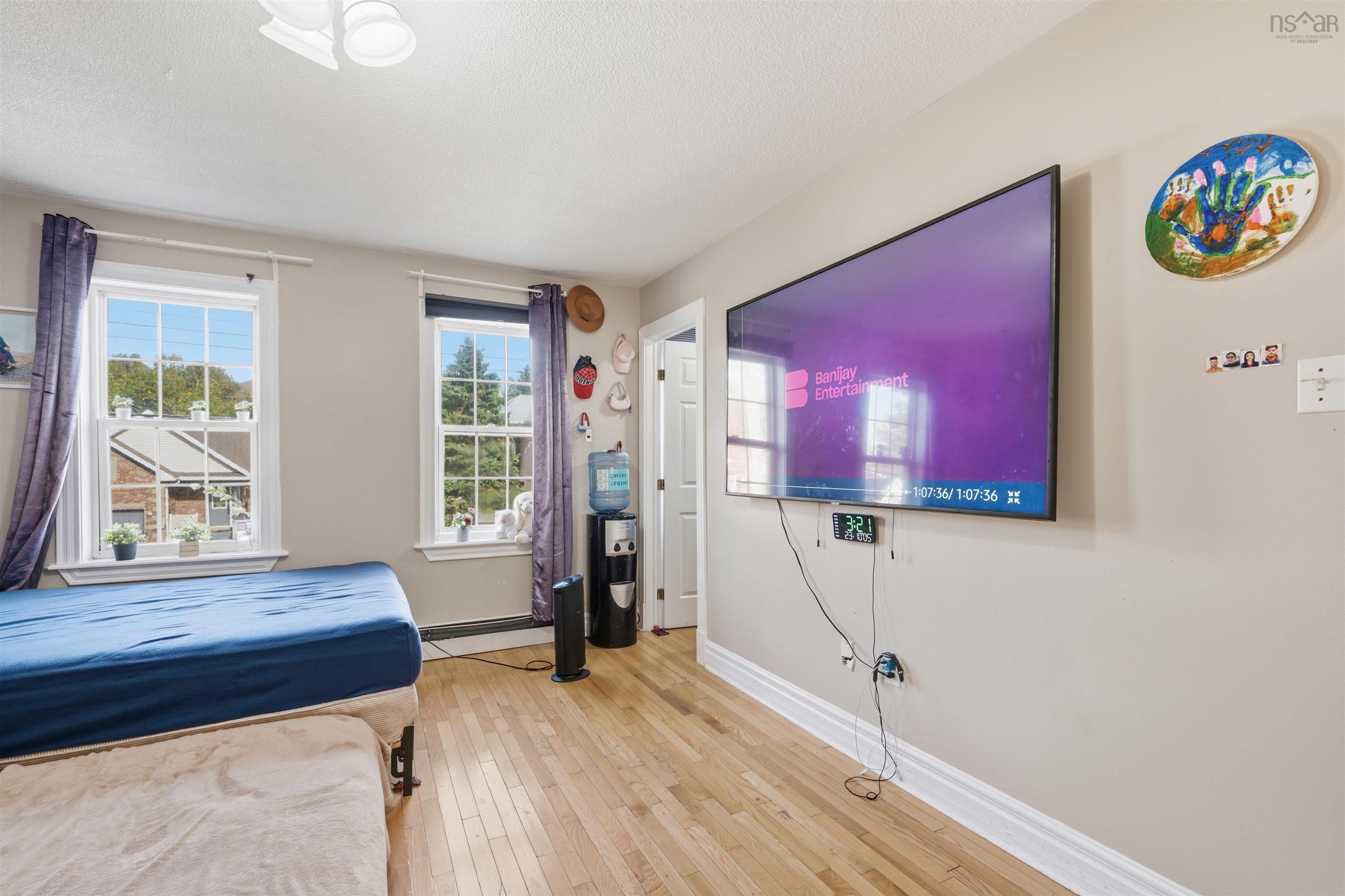 34 Lancaster Drive, Clayton Park, NS (MLS® 202626151) — Neutral wall-toned room featuring wood-finish flooring, two double-hung windows with white casings, and an interior door with multi-panel detailing