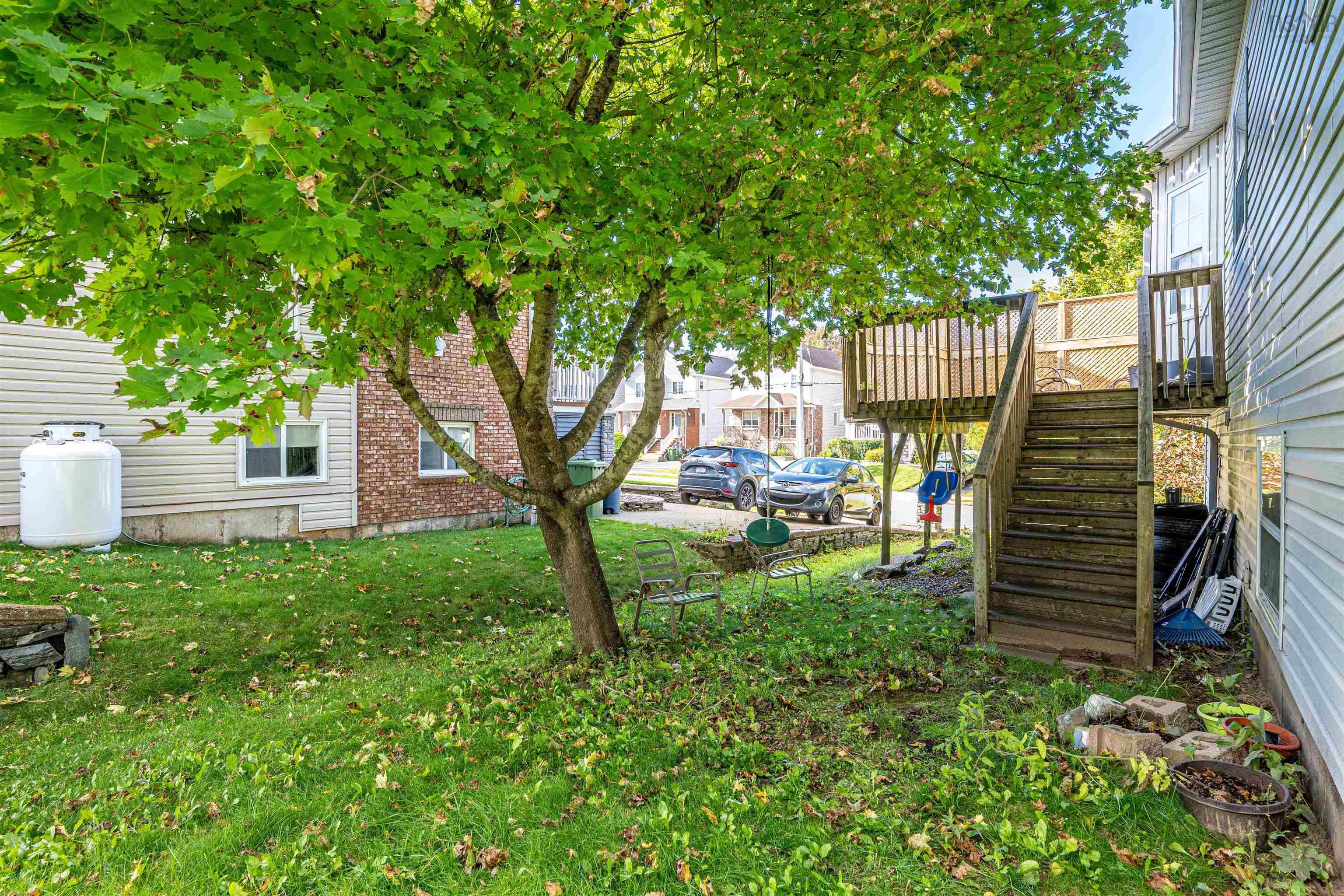 34 Lancaster Drive, Clayton Park, NS (MLS® 202626151) — Rear yard featuring a mature shade tree, raised wooden deck, and wooden staircase