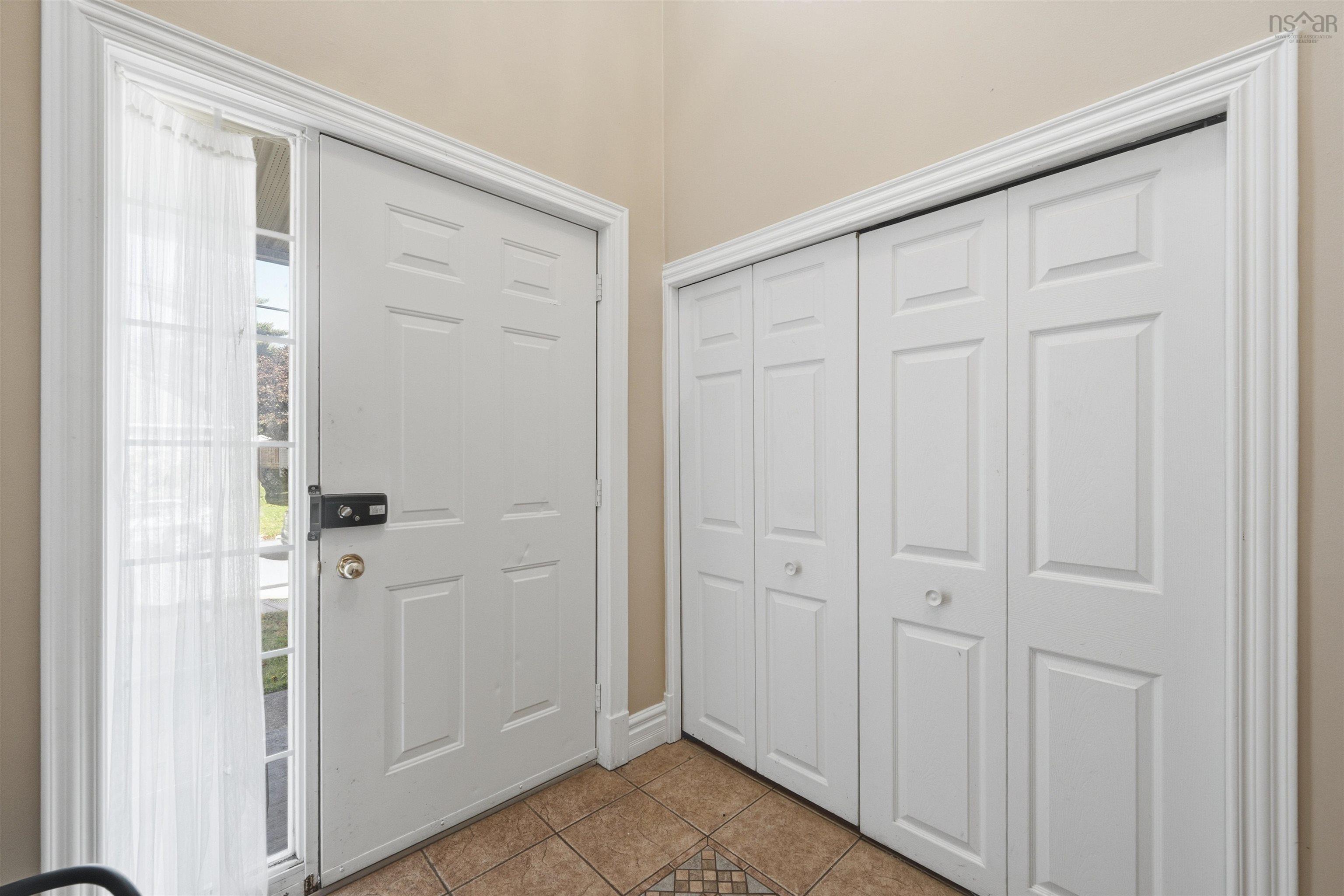 34 Lancaster Drive, Clayton Park, NS (MLS® 202626151) — Entryway featuring a white paneled front door, sidelight with grid detailing, double bifold closet doors, and ceramic tile flooring