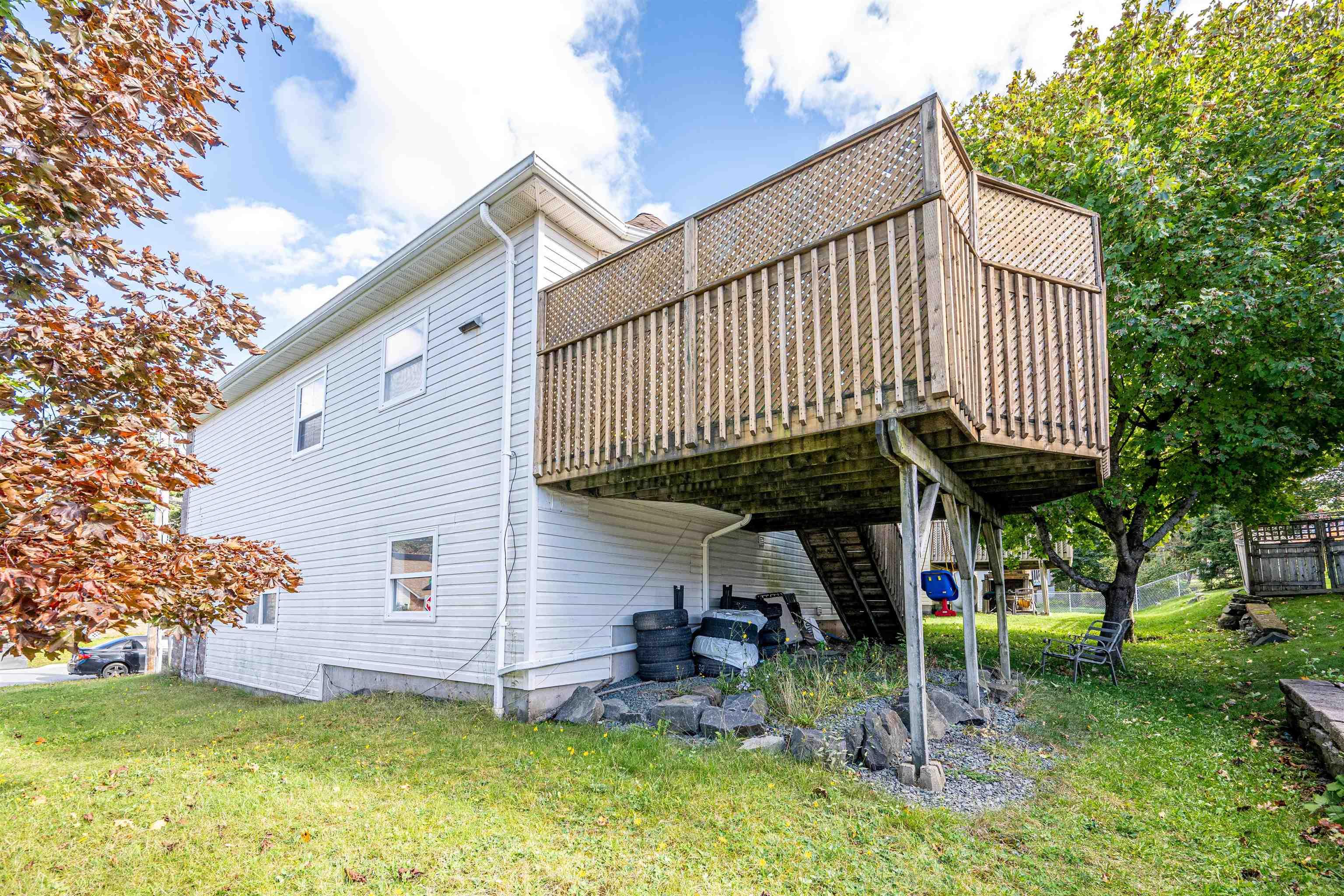 34 Lancaster Drive, Clayton Park, NS (MLS® 202626151) — Raised wood deck featuring lattice privacy screening, wooden staircase, and ground-level support posts, paired with light-colored siding