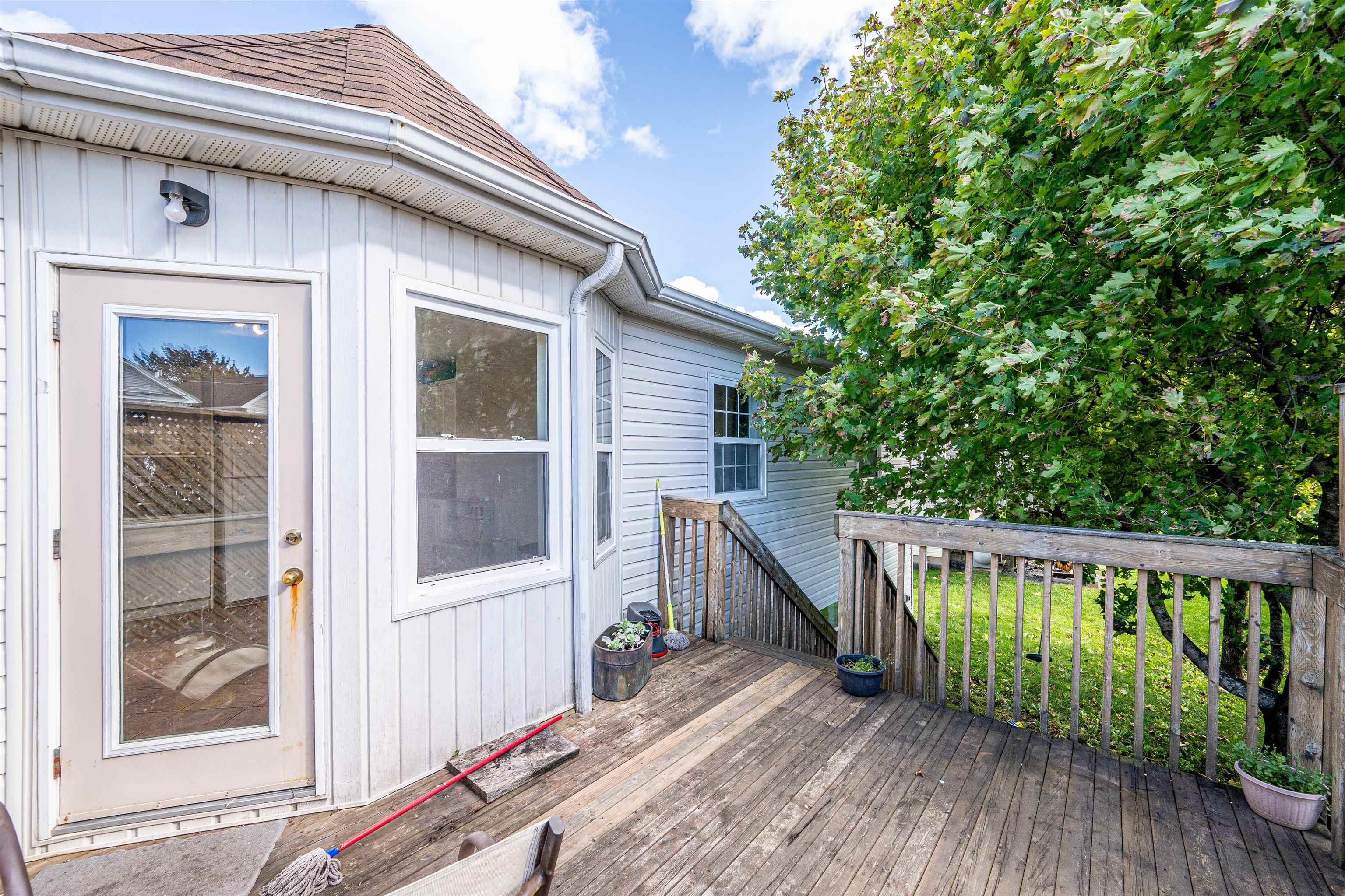 34 Lancaster Drive, Clayton Park, NS (MLS® 202626151) — Exterior wood deck with a wooden perimeter railing, vertical light-colored siding, and a glass-paneled door