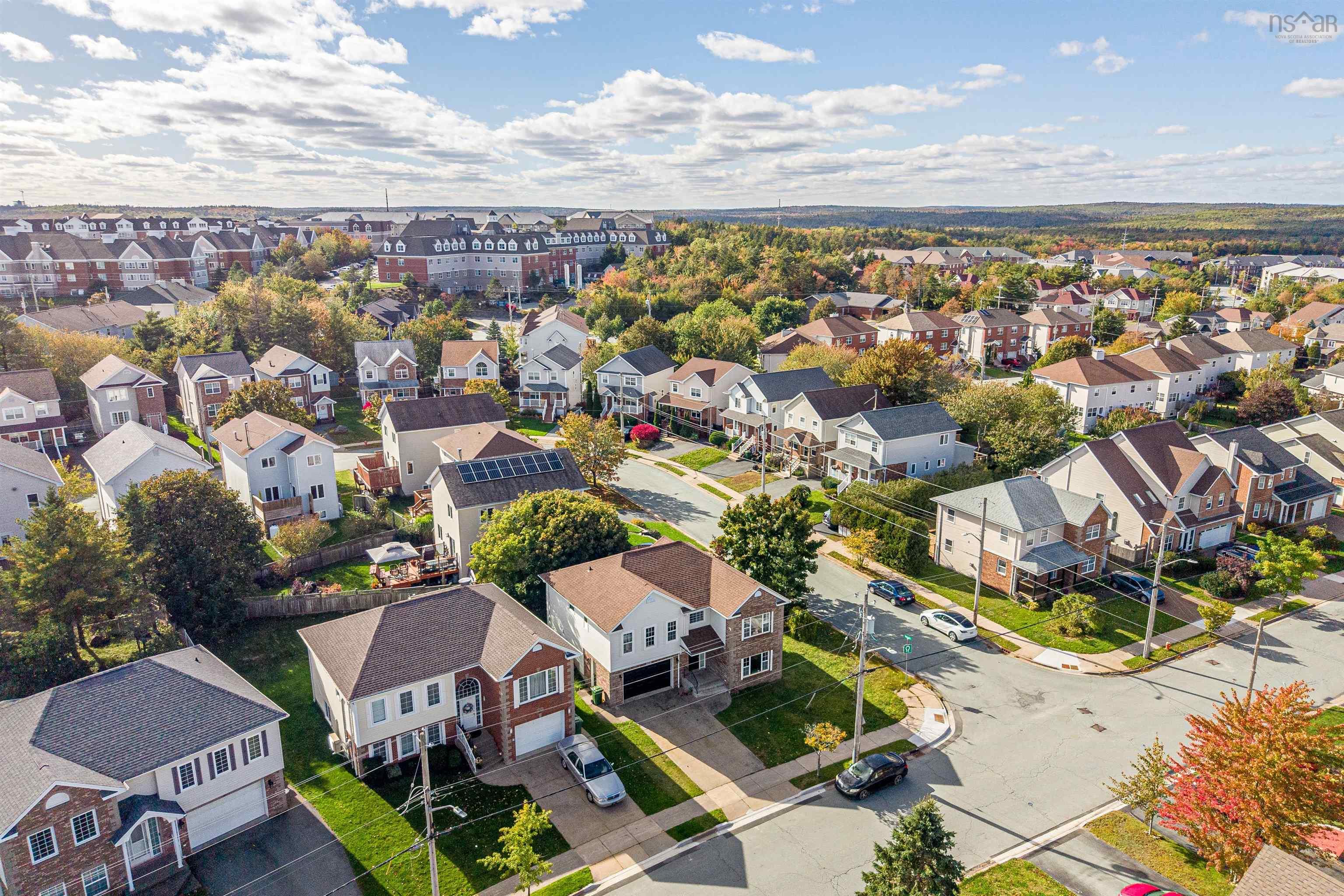 34 Lancaster Drive, Clayton Park, NS (MLS® 202626151) — Aerial perspective of a suburban neighborhood featuring residential homes with multi-gabled rooflines, attached garages, paved driveways, and established mature trees
