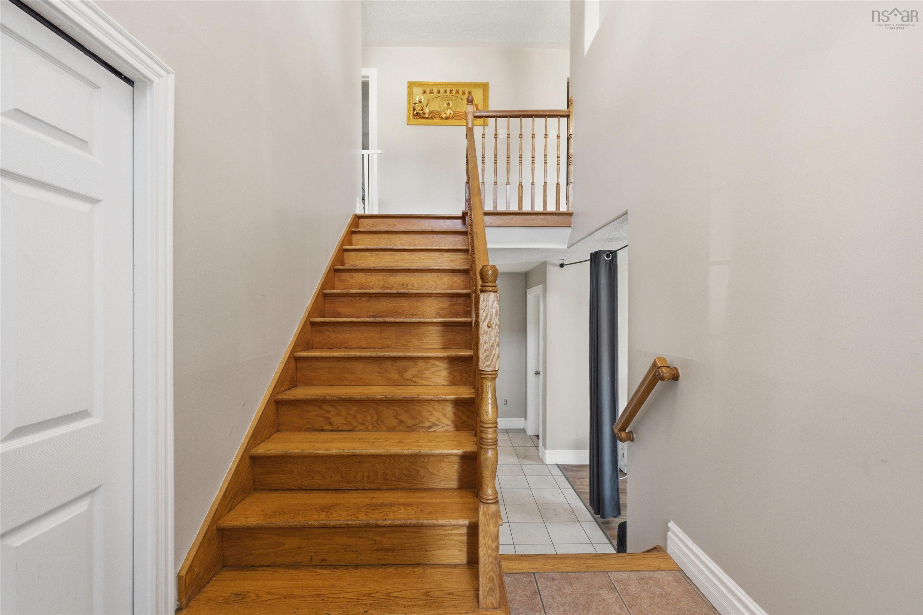 34 Lancaster Drive, Clayton Park, NS (MLS® 202626151) — Staircase featuring natural wood treads and railing, integrated spindle balusters, and neutral-toned wall finish