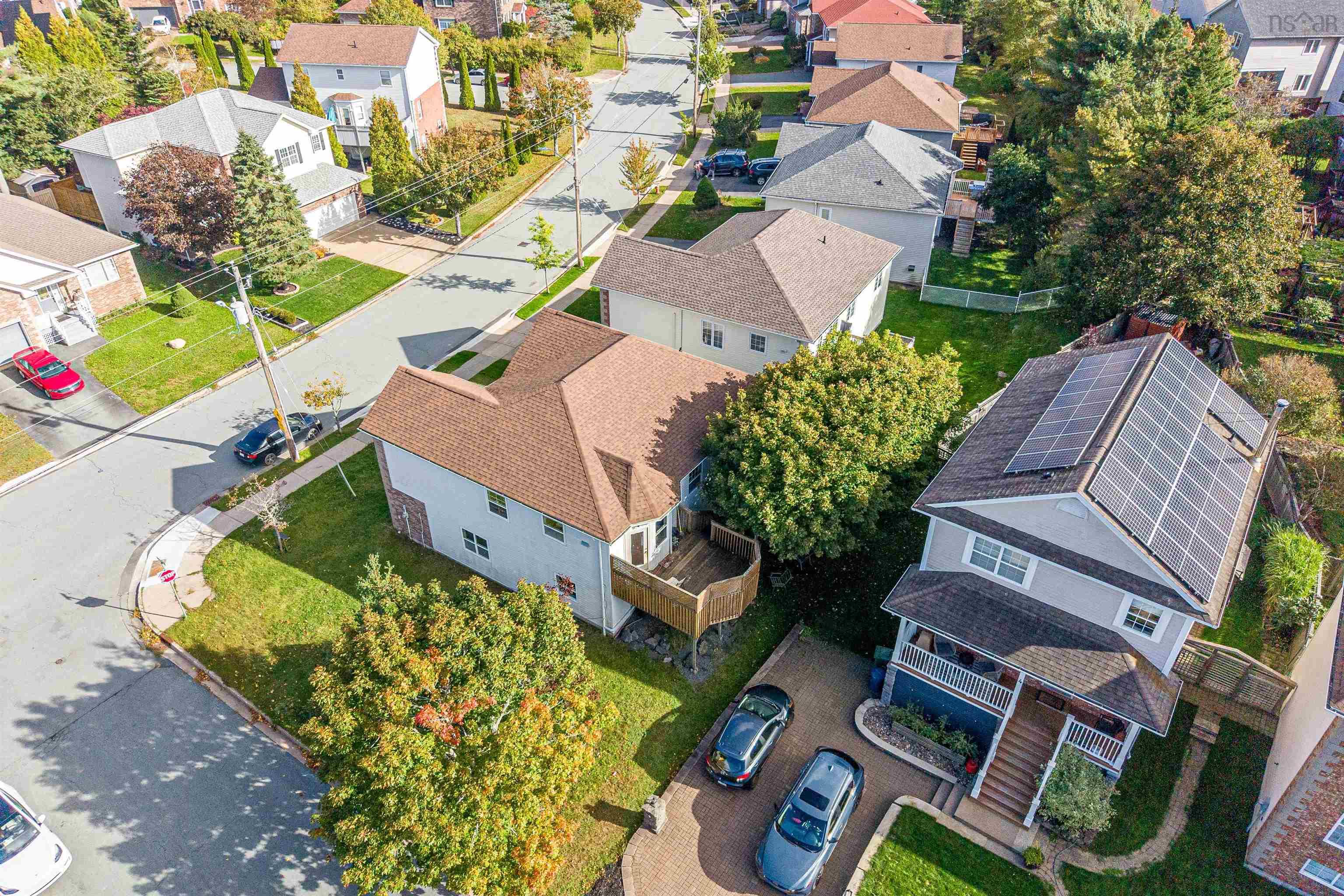 34 Lancaster Drive, Clayton Park, NS (MLS® 202626151) — Aerial perspective featuring a two-story residence with rooftop solar panels, a raised wood deck, stone-paved driveway, and a fenced yard