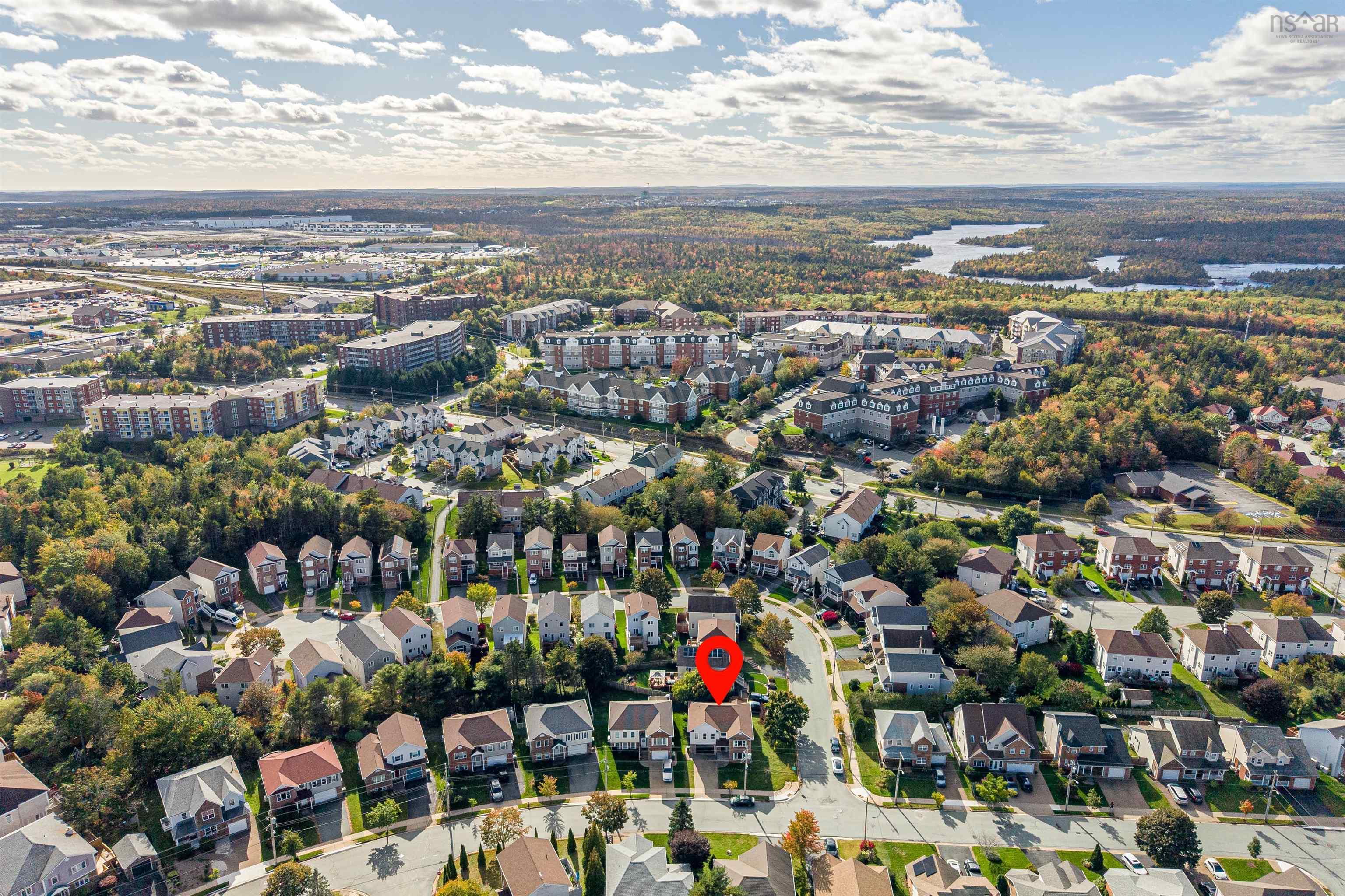 34 Lancaster Drive, Clayton Park, NS (MLS® 202626151) — Aerial perspective of a residential neighborhood featuring multi-story homes, paved streets, dense surrounding foliage, and water bodies in the distance