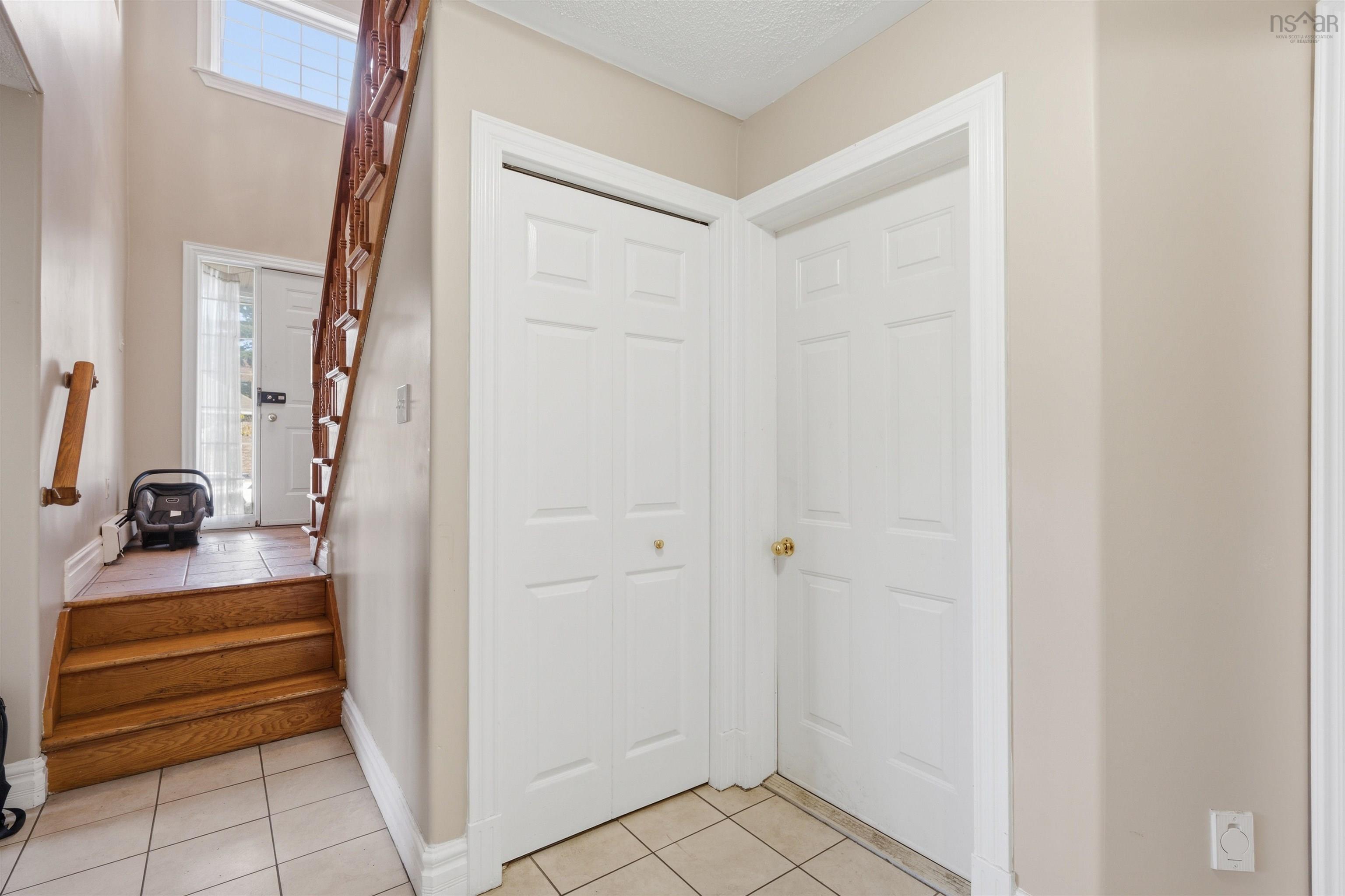 34 Lancaster Drive, Clayton Park, NS (MLS® 202626151) — Foyer featuring ceramic tile flooring, a staircase with wood-finish treads and railing, and dual interior closet doors