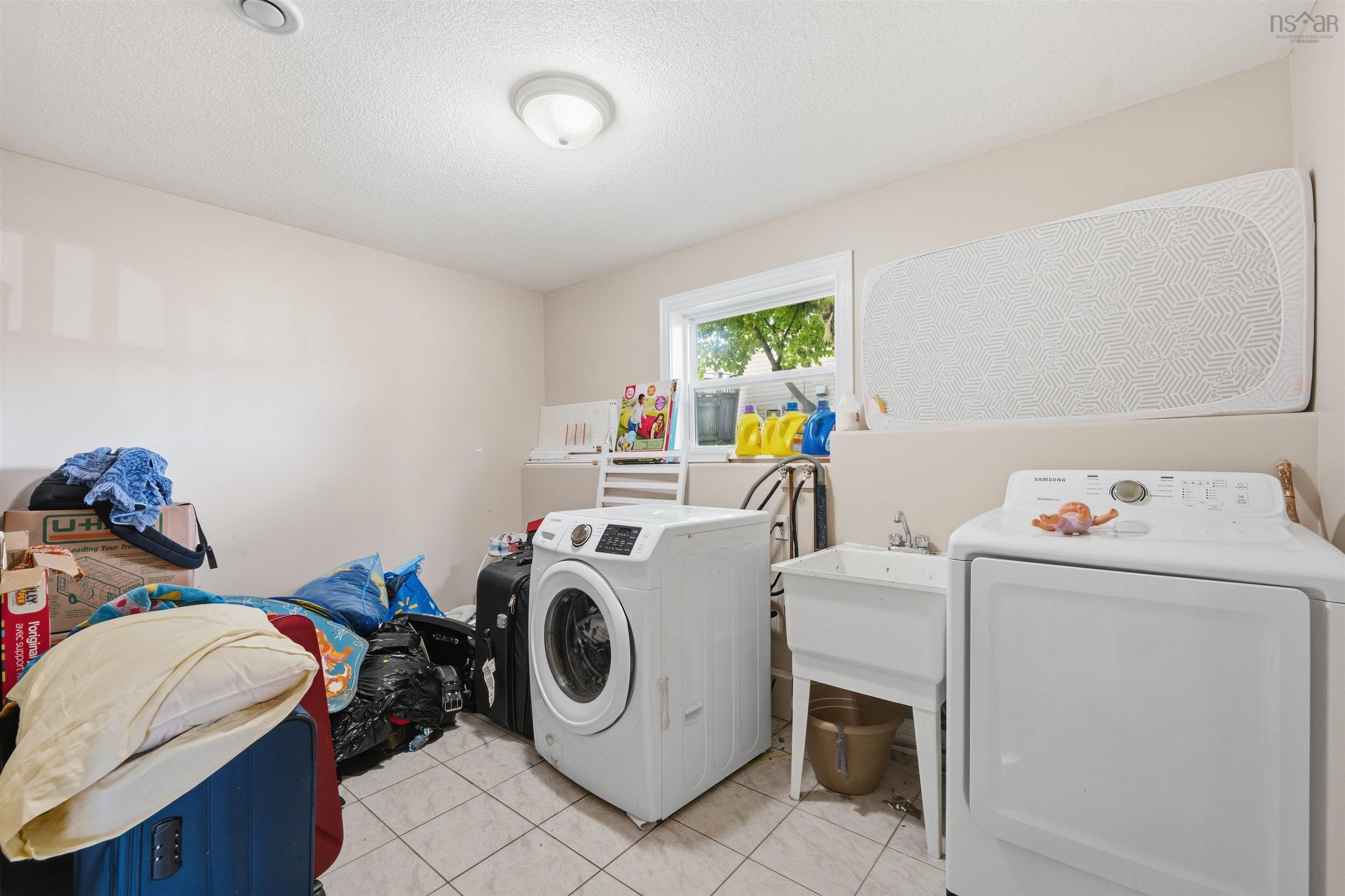 34 Lancaster Drive, Clayton Park, NS (MLS® 202626151) — Laundry room featuring light-colored tile flooring, a white utility sink with a chrome faucet, and a single-pane window