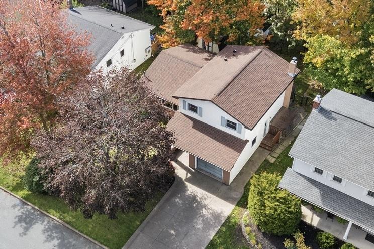24 Rossi Drive, Dartmouth, NS (MLS® 202626410) — Two-story residence featuring a shingled roof, stucco siding, an attached garage, a concrete driveway, and mature trees
