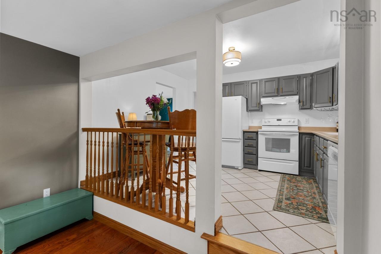 24 Rossi Drive, Dartmouth, NS (MLS® 202626410) — Kitchen featuring dark cabinetry, white built-in appliances, ceramic tile flooring, and a decorative wood spindle railing