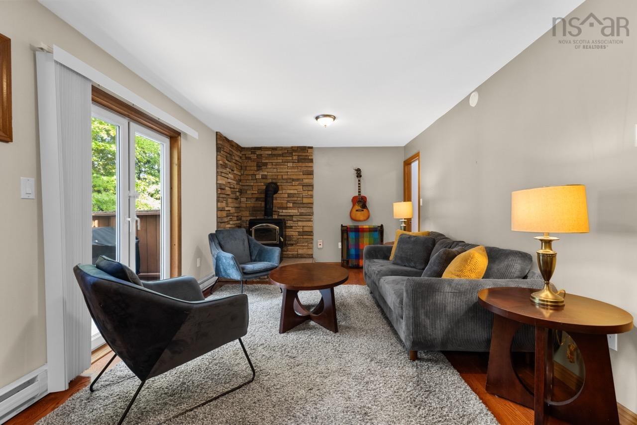 24 Rossi Drive, Dartmouth, NS (MLS® 202626410) — Living space featuring wood-finish flooring, a floor-to-ceiling textured stone accent wall, and a wood-burning stove