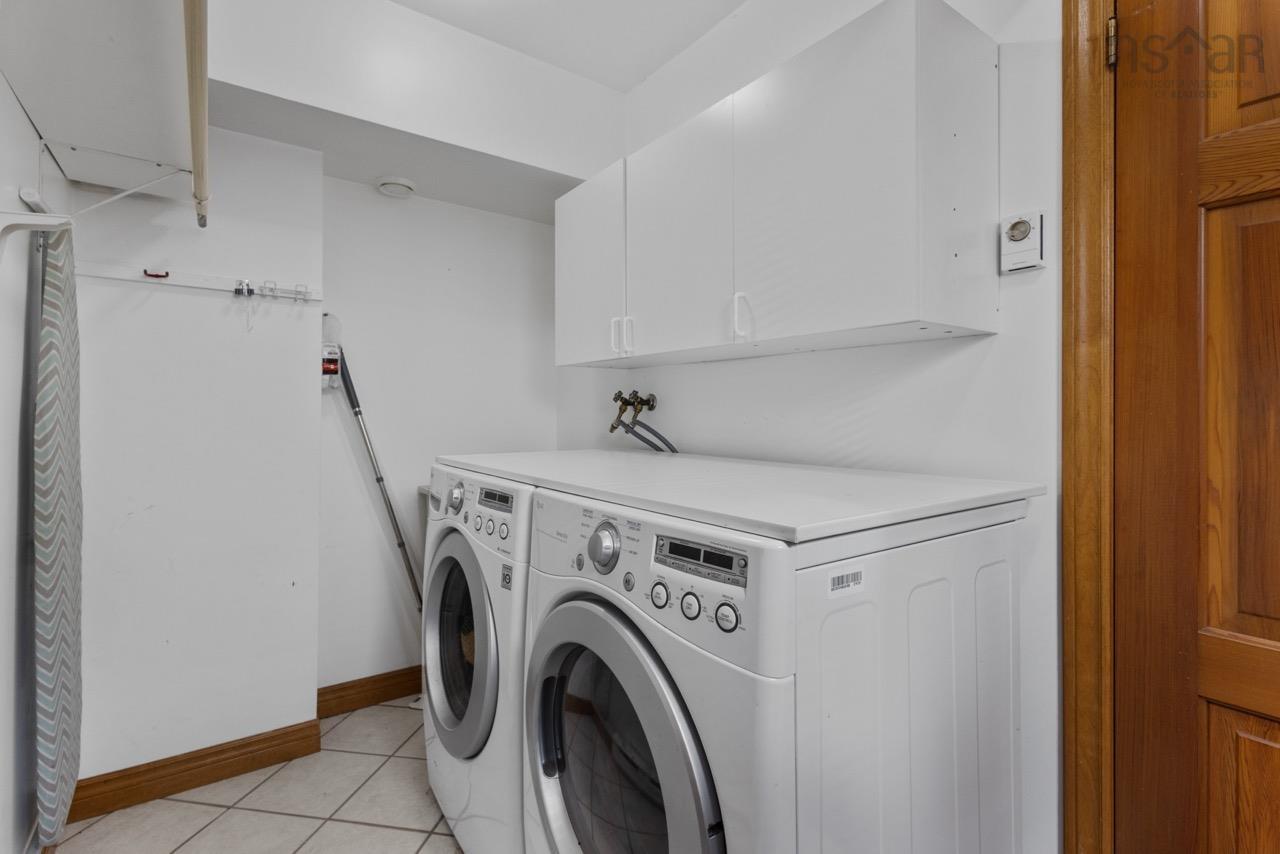 24 Rossi Drive, Dartmouth, NS (MLS® 202626410) — Laundry area featuring white wall-mounted cabinetry, tile flooring, and a natural wood door with matching trim