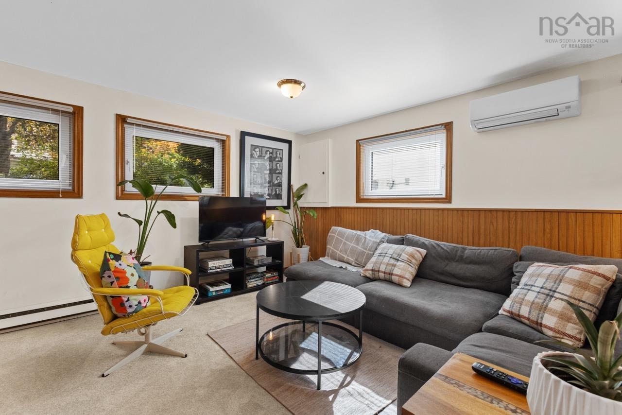 24 Rossi Drive, Dartmouth, NS (MLS® 202626410) — Interior space featuring wood-paneled wainscoting, wall-mounted ductless climate control system, neutral carpeting, and three windows framed in wood trim