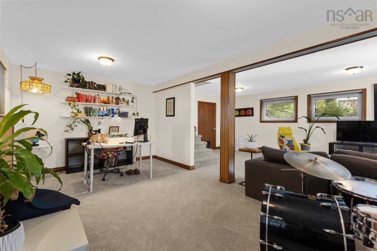 24 Rossi Drive, Dartmouth, NS (MLS® 202626410) — Open floor plan featuring neutral wall finishes, carpeted flooring, built-in wall shelving, a decorative wooden support column, and dual windows