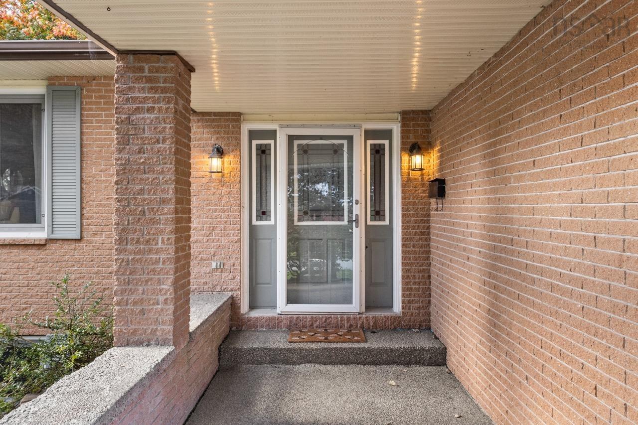 24 Rossi Drive, Dartmouth, NS (MLS® 202626410) — Covered entryway featuring a brick facade, concrete porch, and a decorative glass-panel front door with matching side panels