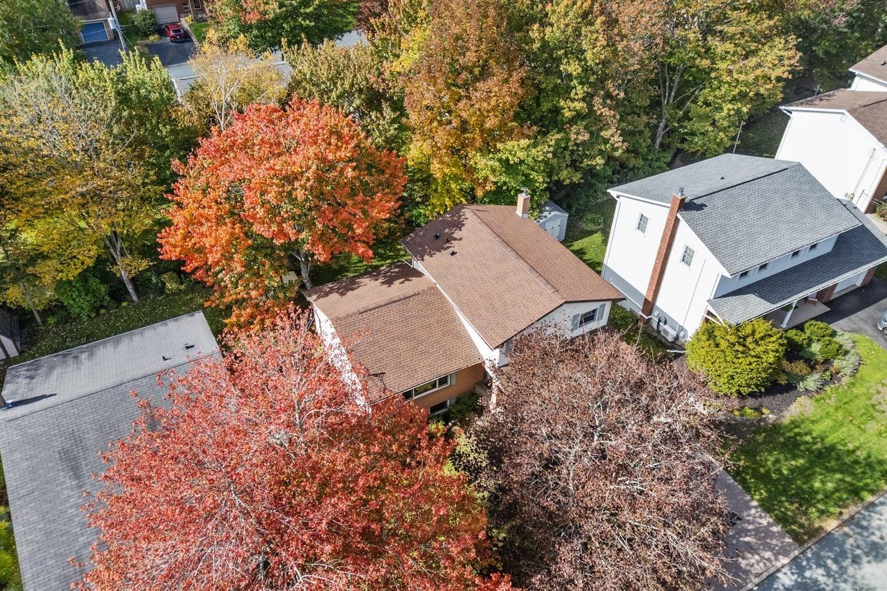 24 Rossi Drive, Dartmouth, NS (MLS® 202626410) — Aerial perspective of a multi-level residence featuring a brown shingled roof, a chimney stack, and mature deciduous trees