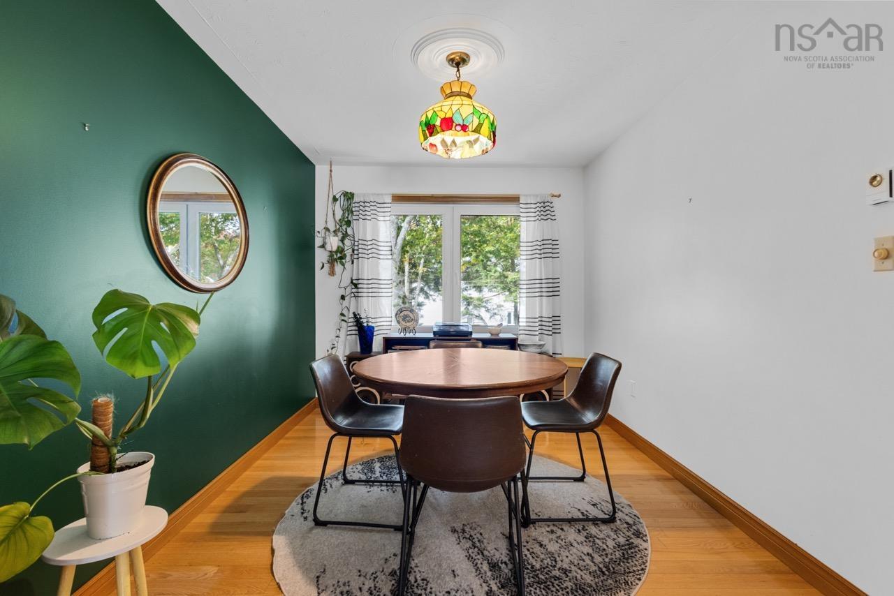 24 Rossi Drive, Dartmouth, NS (MLS® 202626410) — Room featuring wood-finish flooring, a vibrant accent wall, stained-glass hanging light fixture with a decorative ceiling medallion, and large windows