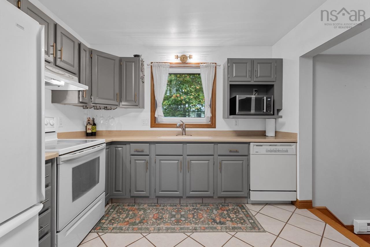 24 Rossi Drive, Dartmouth, NS (MLS® 202626410) — Kitchen featuring grey shaker-style cabinetry, solid-surface countertops, tile flooring, and a window centered above the stainless steel sink