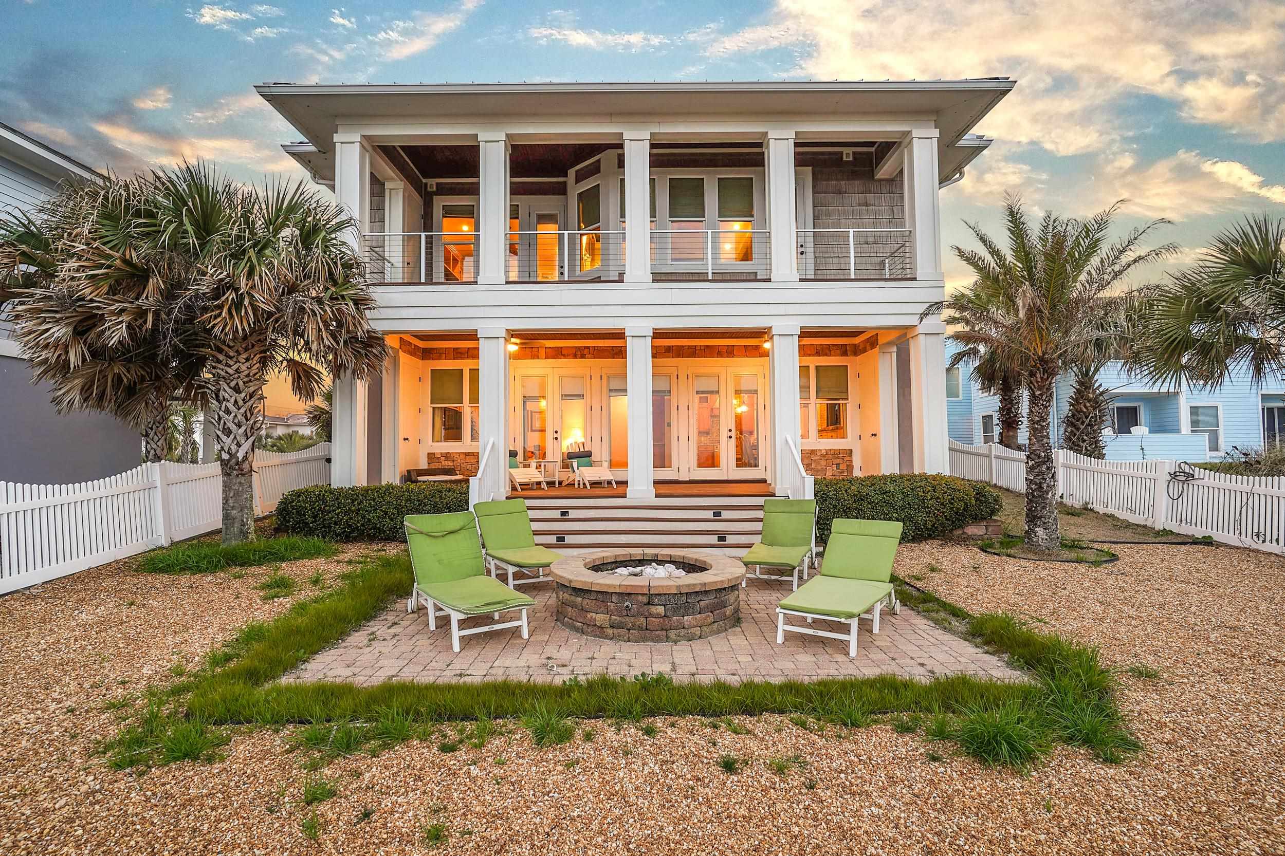 Back of property at dusk featuring a fenced backyard, a patio, a fire pit, and a balcony