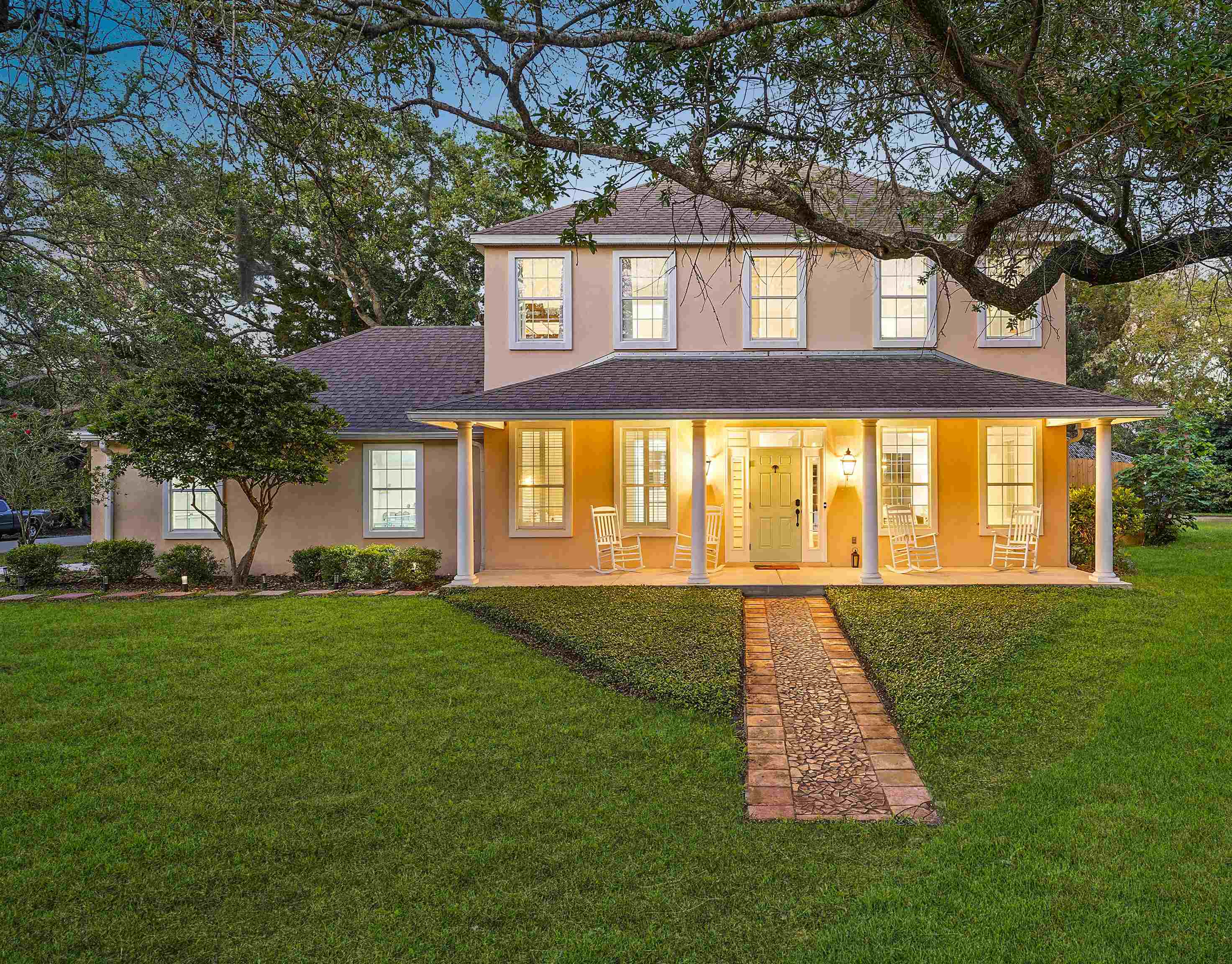 View of front of property featuring a porch, roof with shingles, stucco siding, and a front lawn Front Of Structure