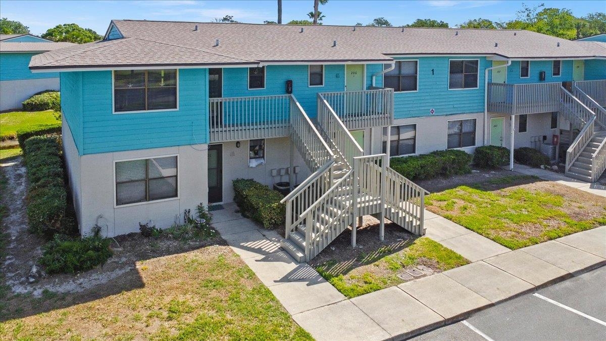 Multi-unit building featuring a turquoise siding upper level and a light-colored lower level Front Of Structure