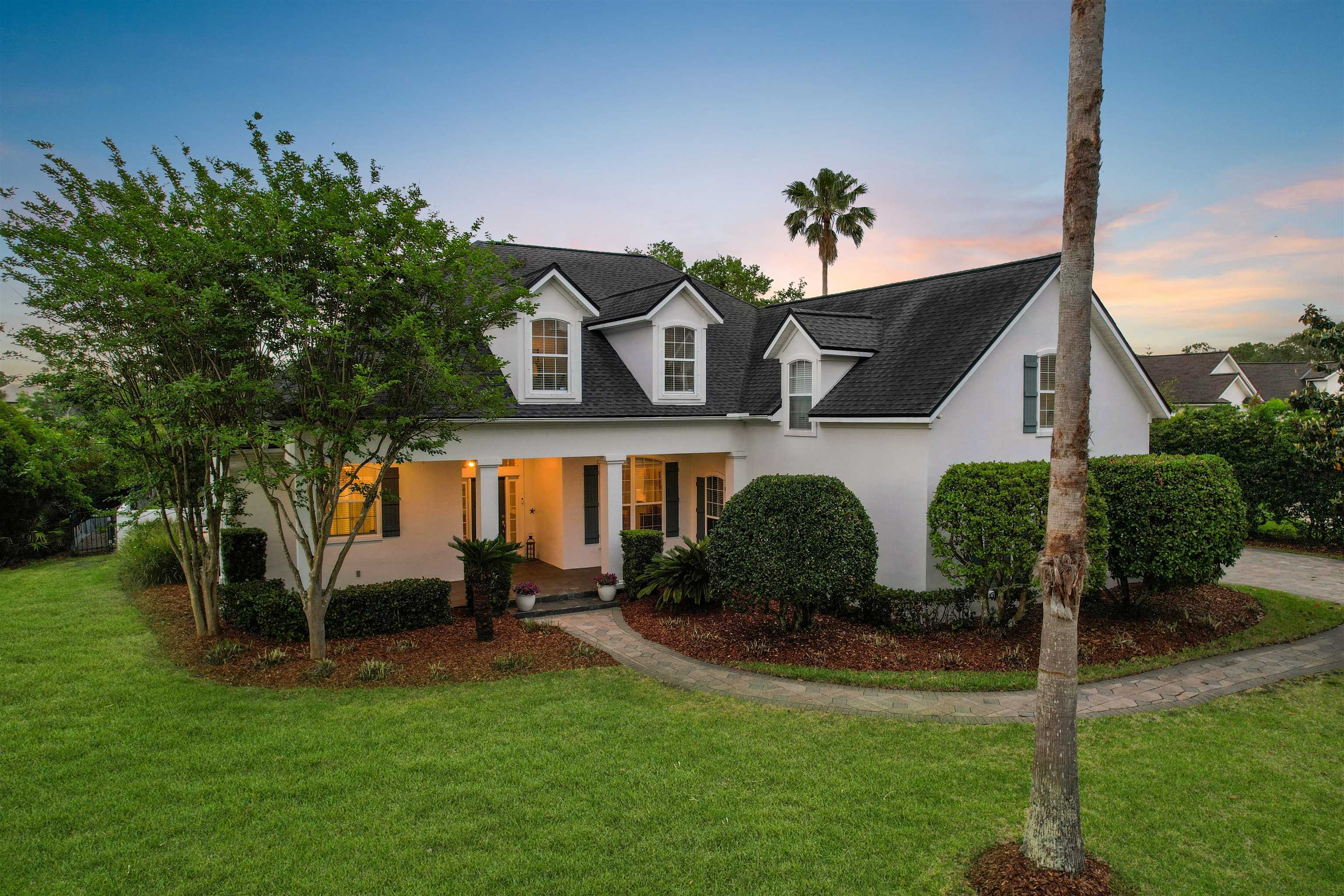 White exterior residence featuring a covered front porch with columns, a dark shingle roof, and multiple dormer windows