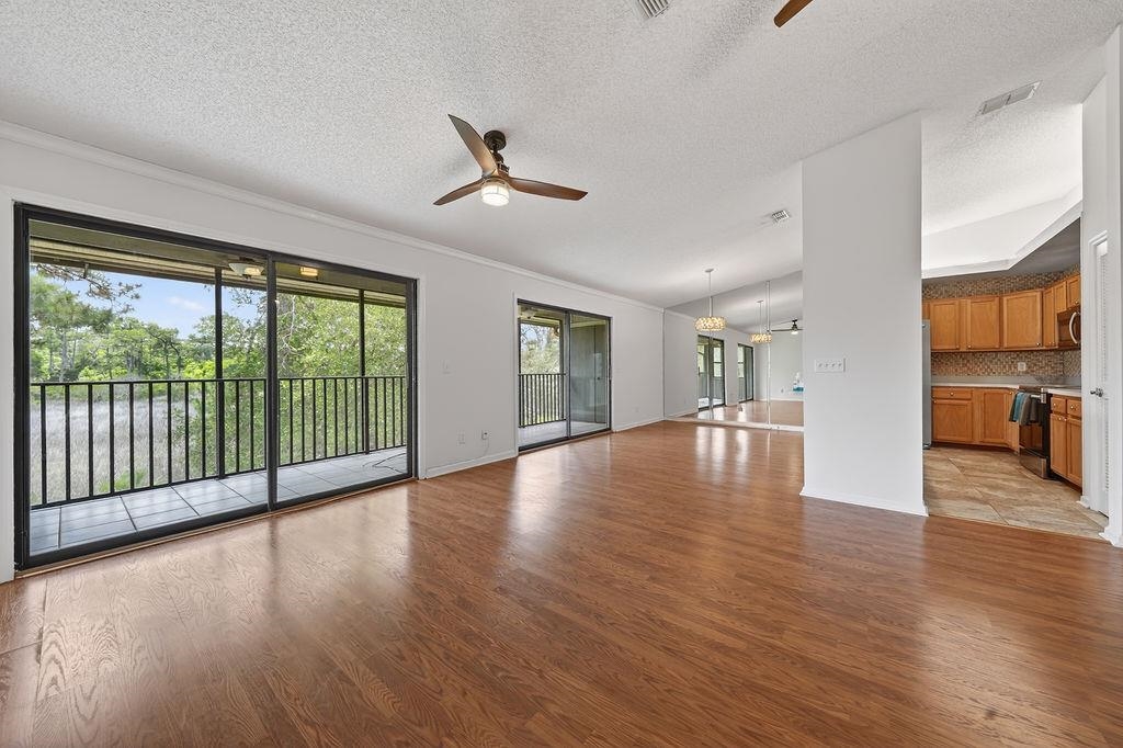 Spacious interior featuring wood-finish flooring, white walls, and a ceiling fan Living Room