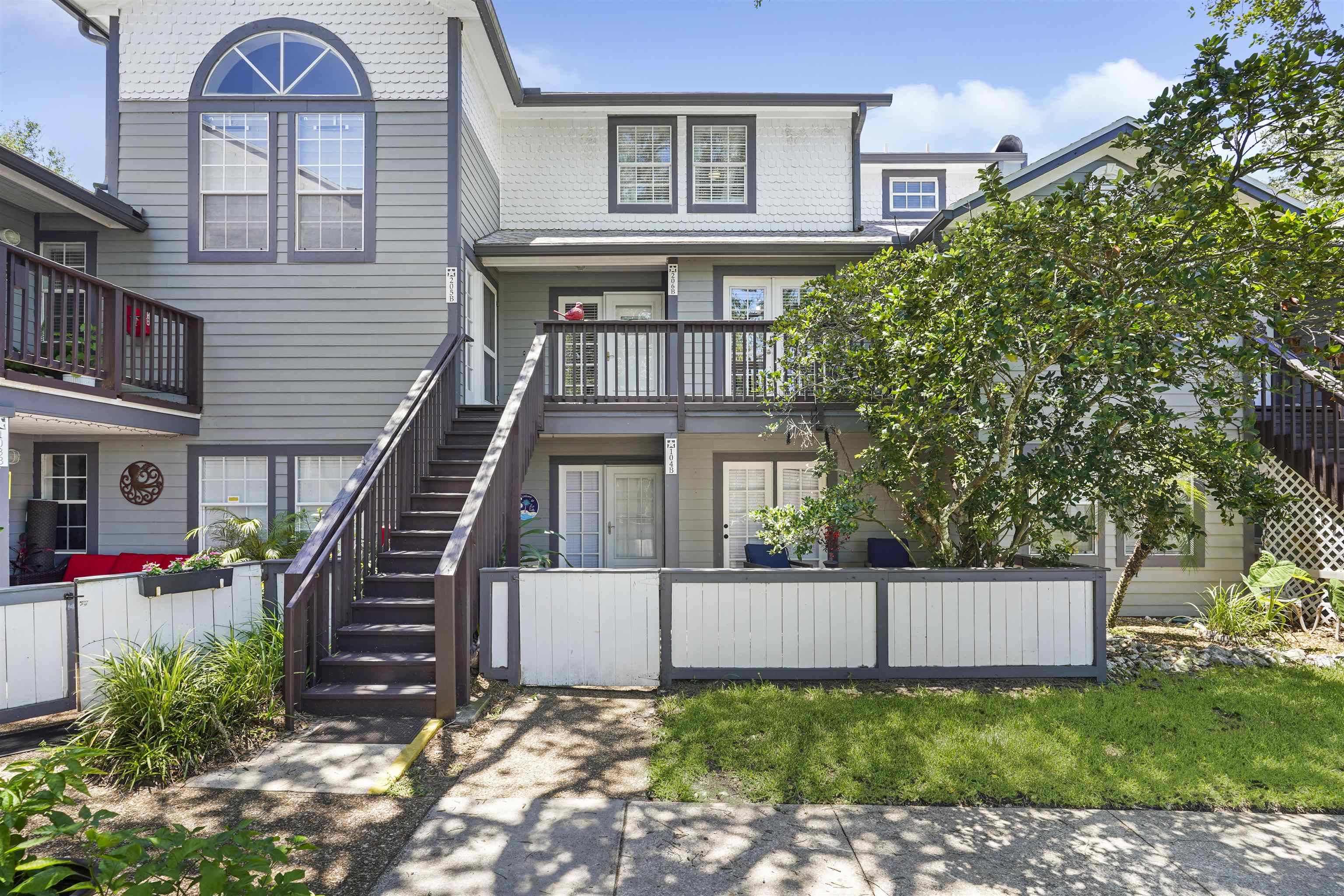 Multi-level building exterior featuring gray siding with white trim accents and shingle siding on upper dormers