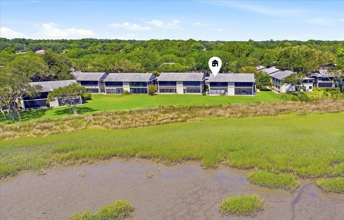 Waterfront property with extensive marshland, lush green lawn, and mature trees Aerial View
