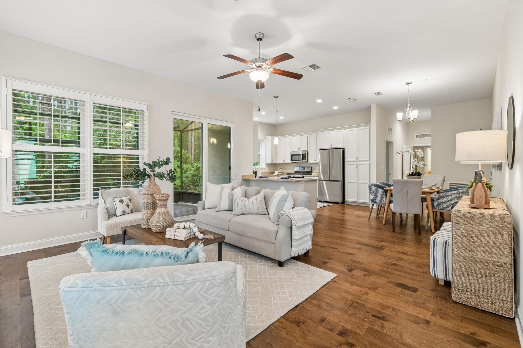 Open-concept living space featuring wood-finish flooring, a contemporary ceiling fan, and a sliding glass door leading to an outdoor area Living Room