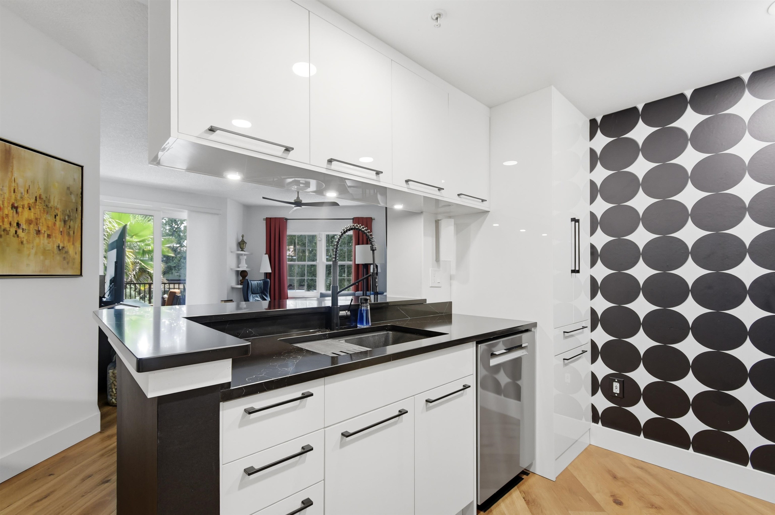 Contemporary kitchen featuring high-gloss white cabinetry, dark stone countertops, and integrated stainless steel appliances Kitchen
