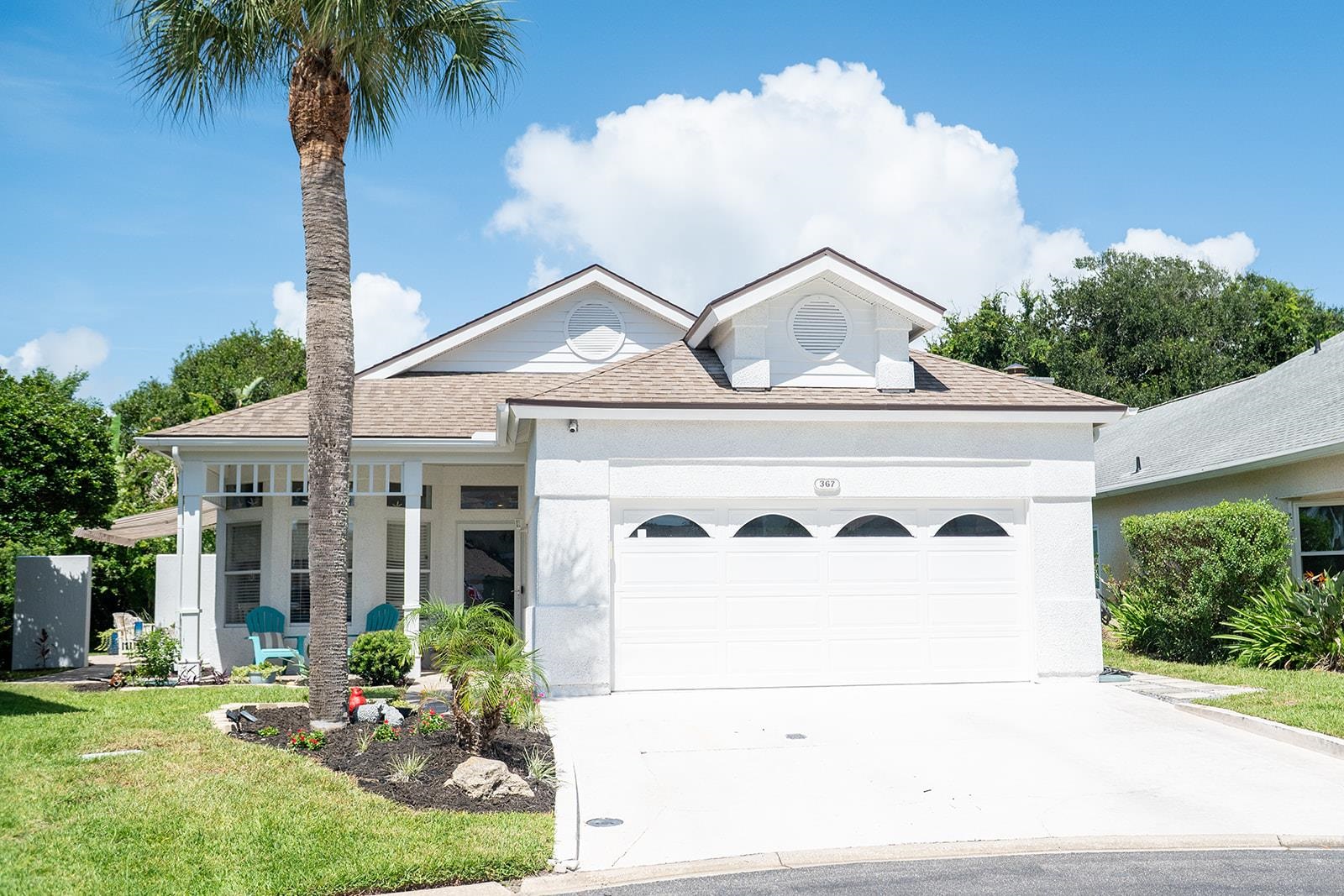 White stucco exterior with a brown shingle roof, integrated garage, concrete driveway, and front porch with columns Front Of Structure