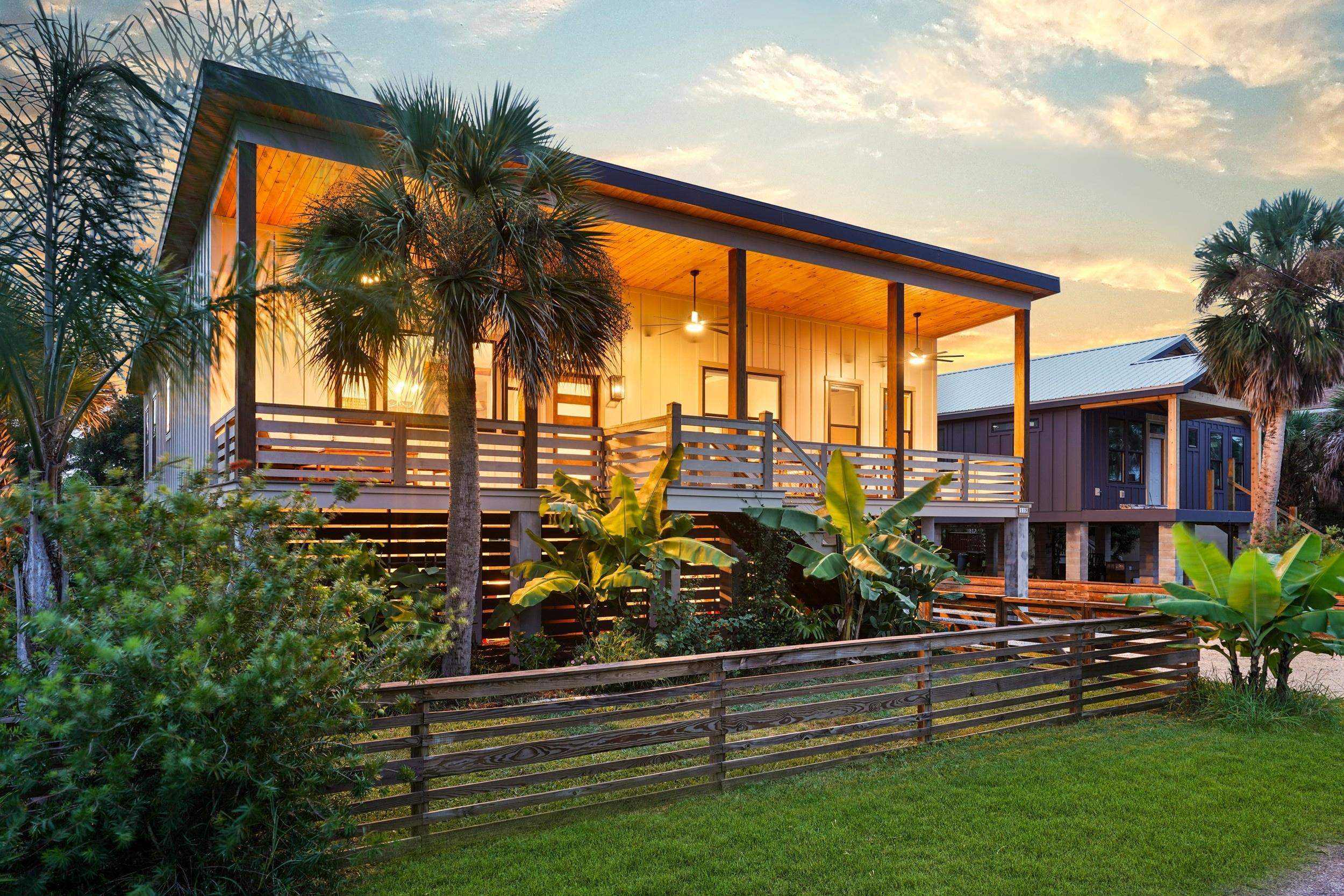 Elevated coastal-style architecture featuring a covered porch with exposed wood ceiling, wood railing, and integrated ceiling fans Back Of Structure