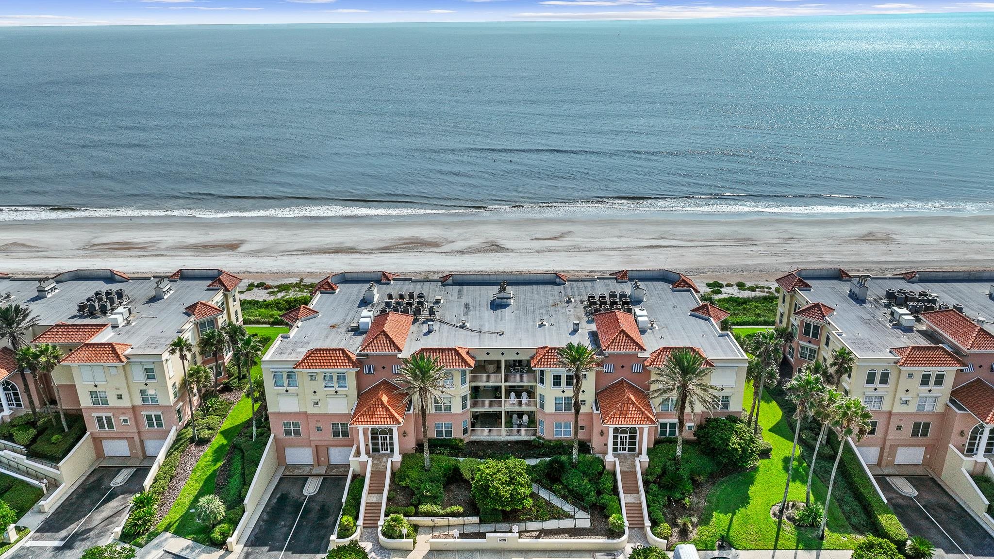 Coastal property with direct beach access, featuring multiple levels, balconies, and terracotta-style roof tiles Aerial View