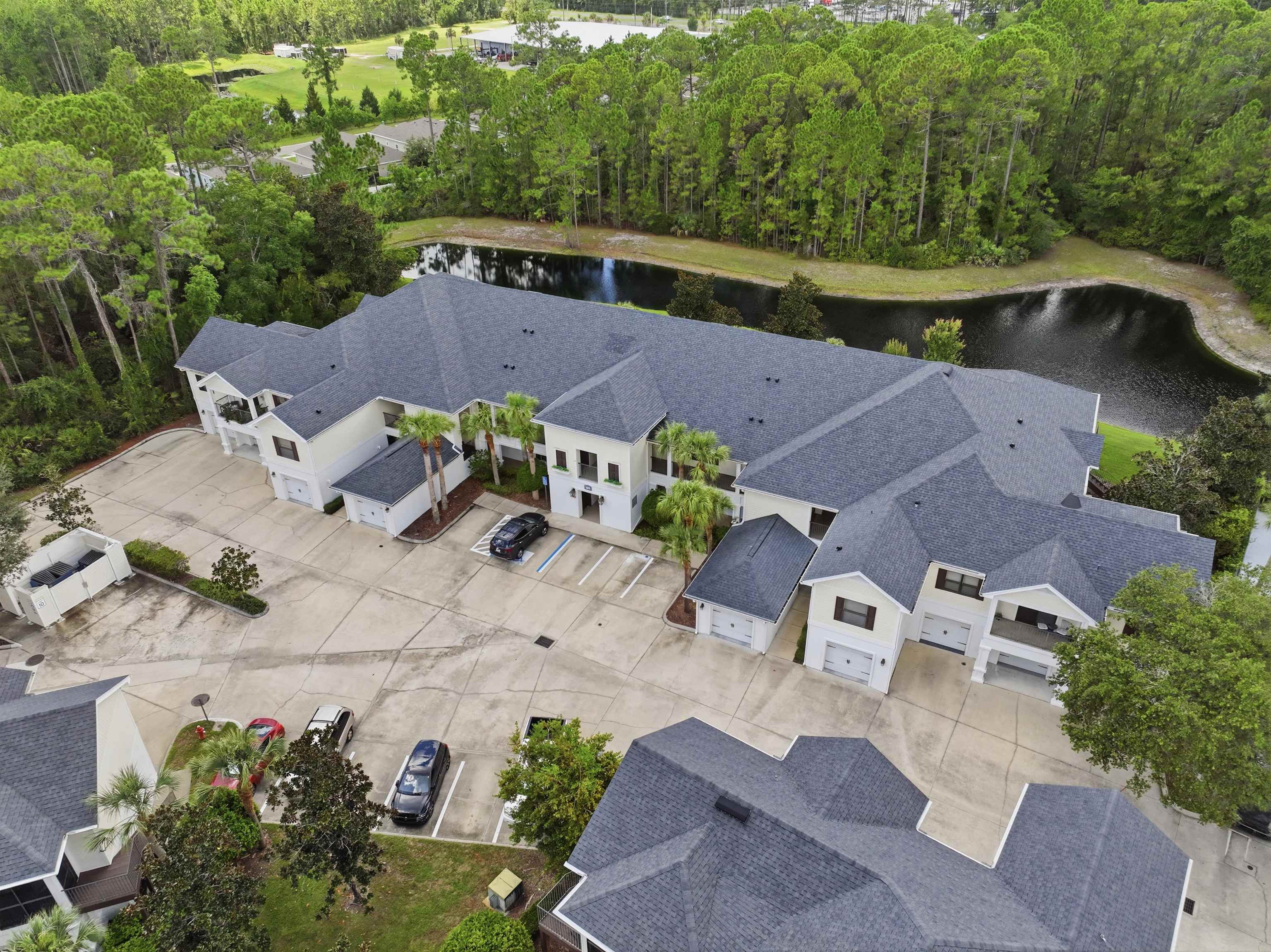 Multi-unit residential complex featuring a shared parking area and individual garages Aerial View