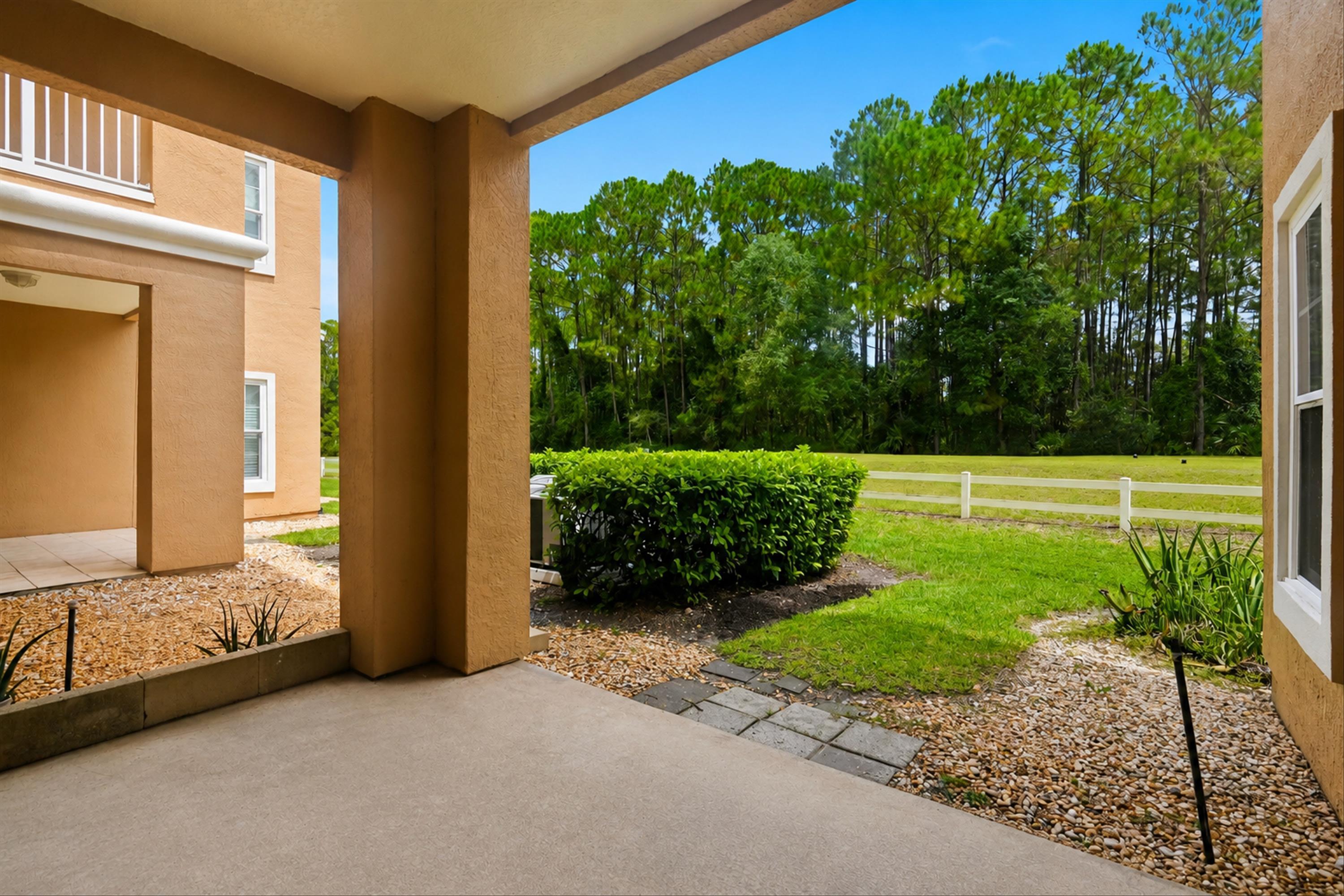 Paved patio with concrete flooring, bordered by decorative gravel and shrubbery Patio