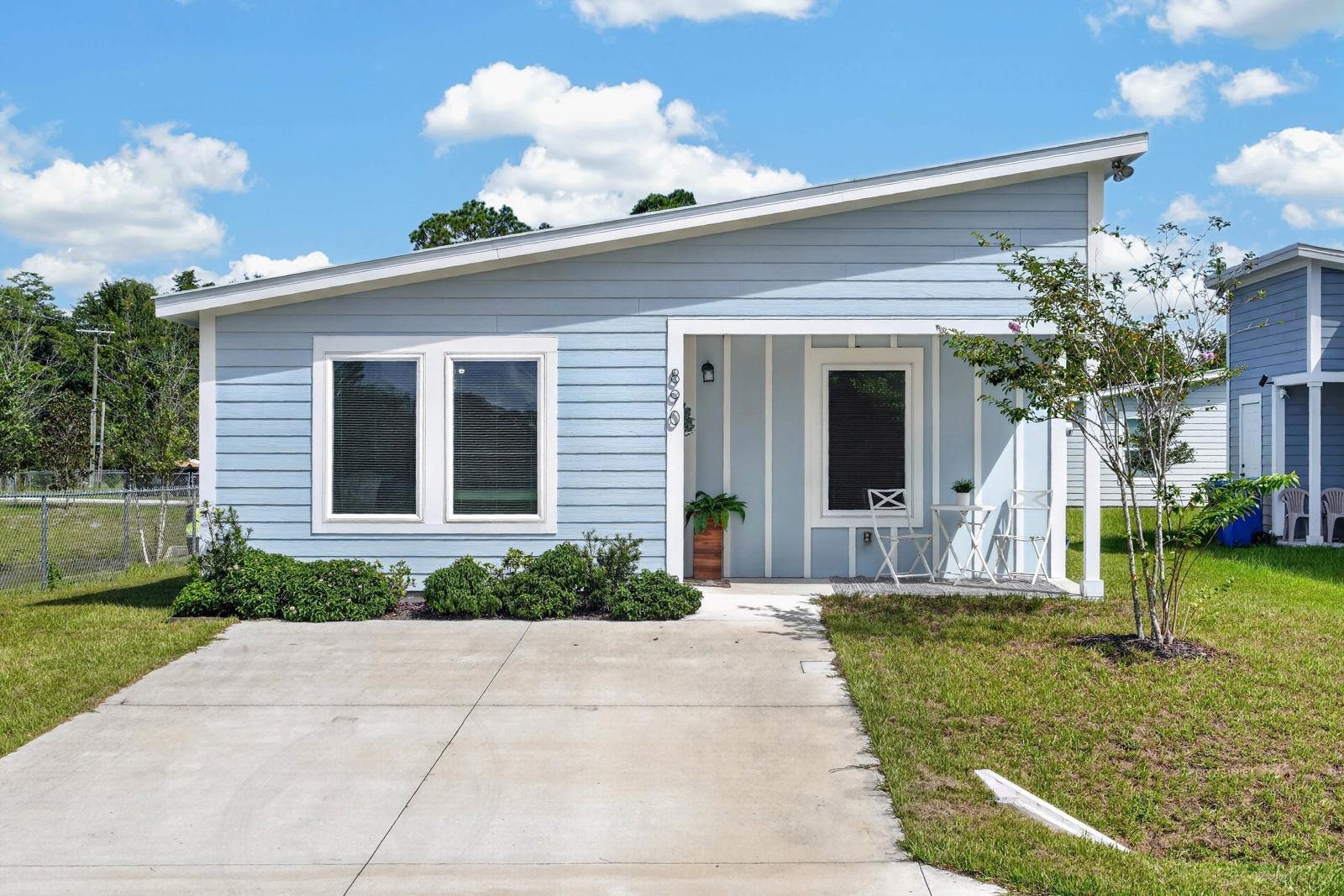 Contemporary exterior with light blue siding, an angled roofline, a concrete driveway, and a covered front porch Front Of Structure