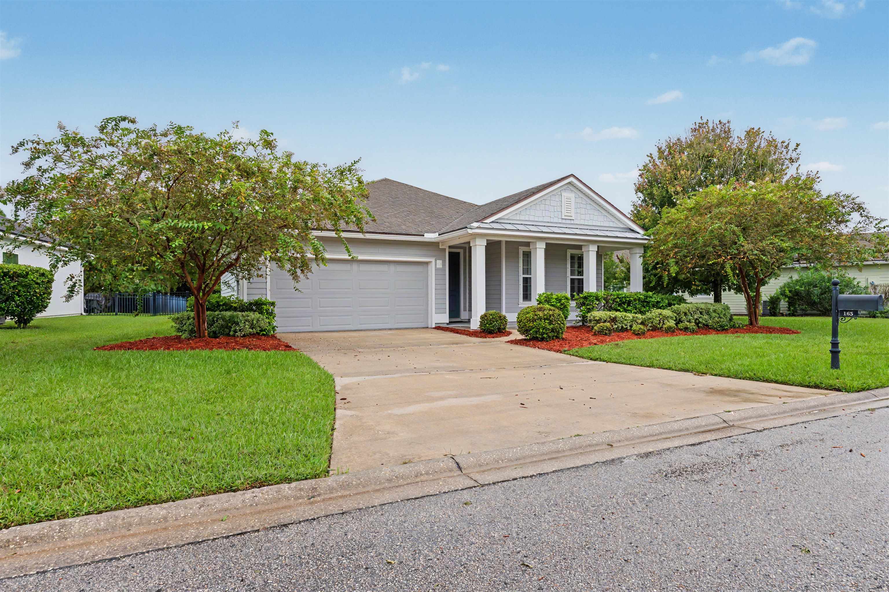 Single-story residence featuring a covered front entry with columns, attached garage, and mature landscaping Front Of Structure