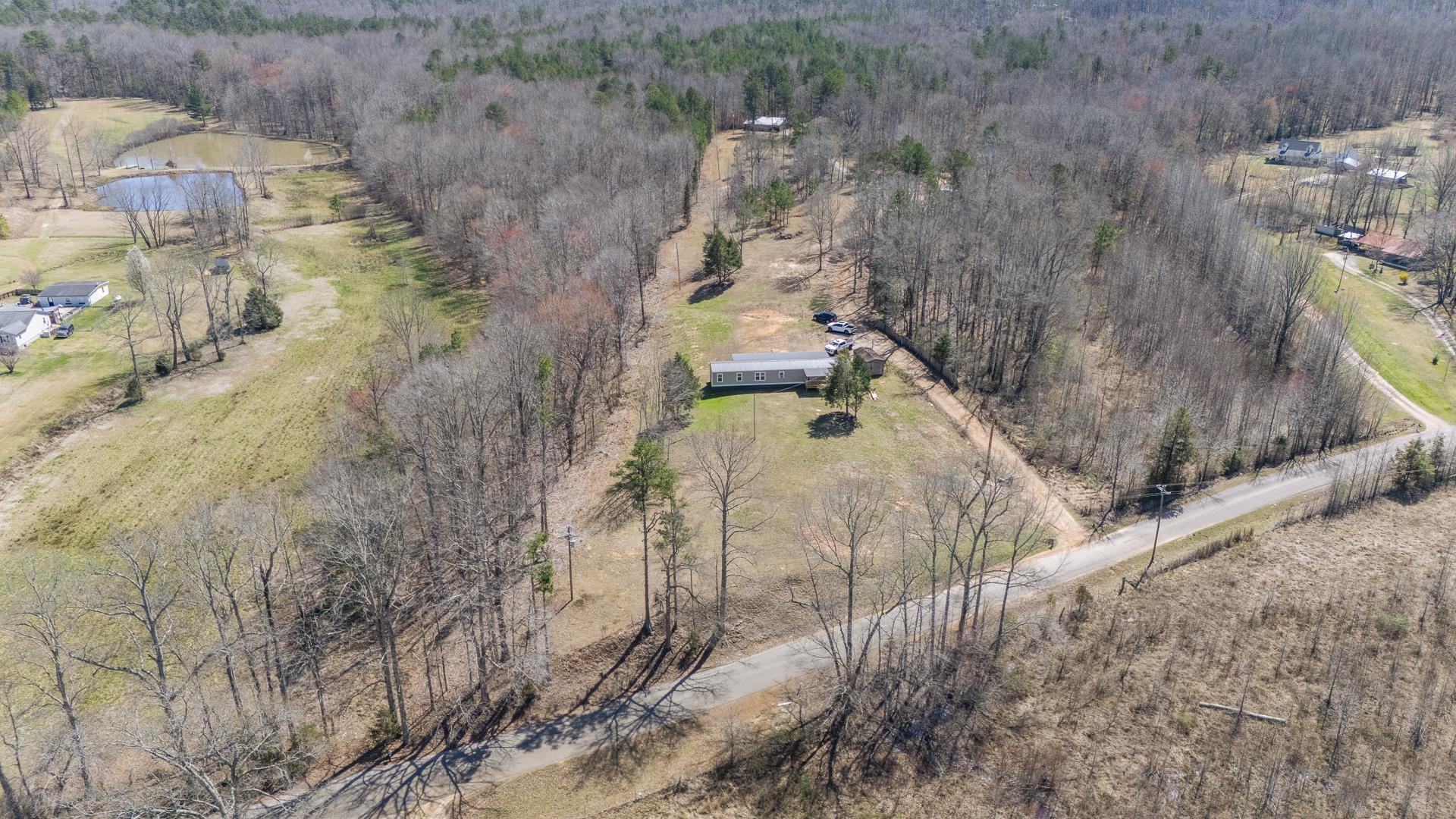 This stunning, completely remodeled home sits on 71 beautiful, mostly wooded acres+/-! All you have to do is MOVE IN! Featuring amazing, covered porches perfect for taking in the views and relaxing, this property offers both comfort and potential. The custom single-wide home is move-in ready with modern upgrades throughout including a tile shower, split bedroom floor plan, recessed lighting, hardwood, tile, & laminate floors, a separate dining area, and comes complete with all kitchen appliances & the washer & dryer! With a spacious barn, convenient storage building, useable block foundation for your next project, and an extended access road, the land provides endless possibilities...whether you want to build additional properties, create a hunting retreat, garden, have a food plot, or just enjoy the serenity of nature! The expansive acreage ensures peace and seclusion while being easily accessible. Don’t miss out on this rare opportunity to own a slice of paradise!