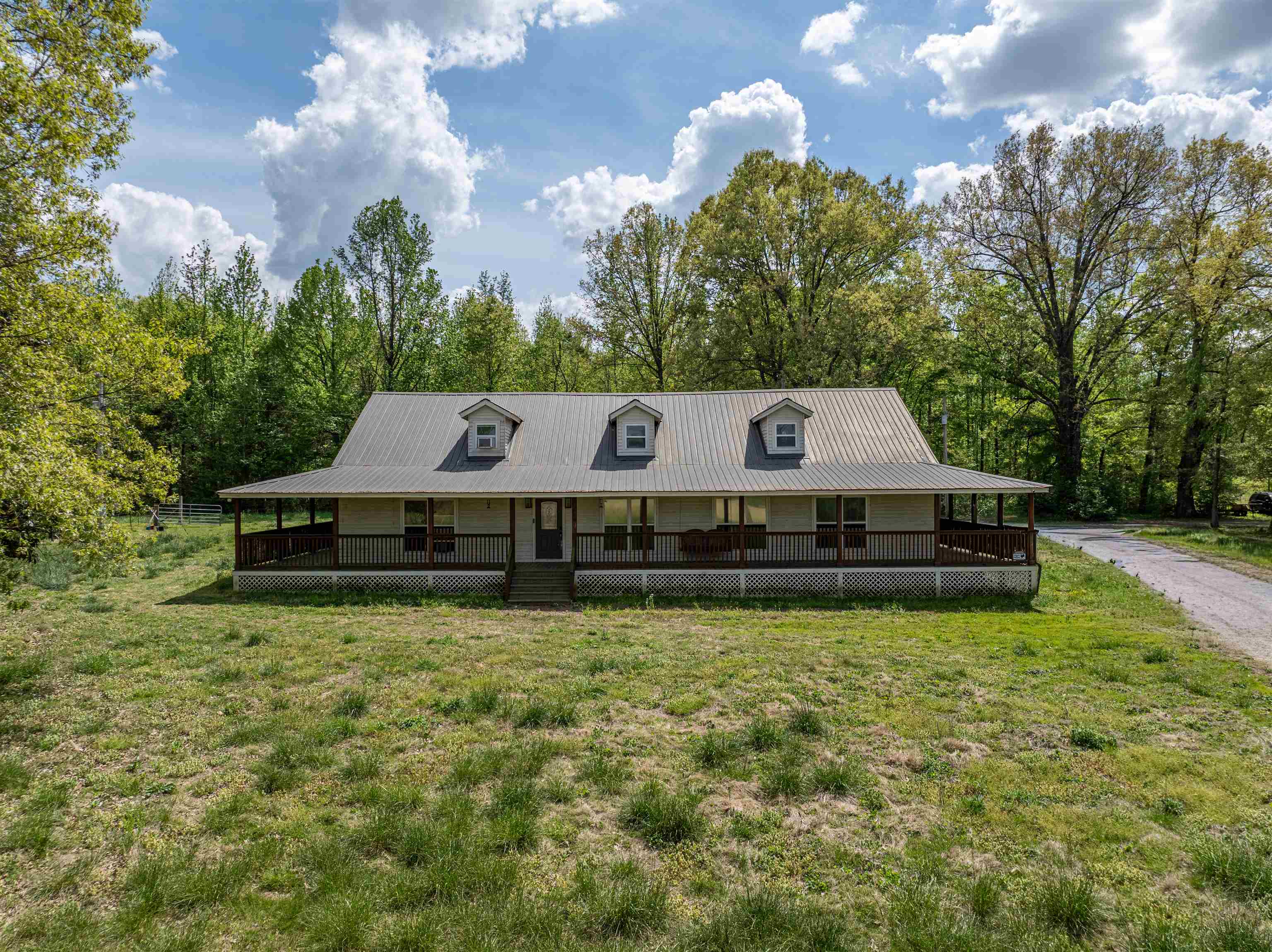 Escape to peaceful country living with this spacious 5-bedroom home on 5 acres in Somerville, TN. This ranch-style property features an open layout with smooth ceilings, recessed lighting, and a welcoming living area.  The kitchen offers granite countertops, stainless steel appliances, a center island w/ storage, and a vaulted ceiling w/ beam accent, with a step-down design that adds character. A separate laundry room and walk-in pantry provide extra convenience and storage.  The primary suite includes tray ceilings, recessed lighting, private backyard access, & an en-suite bath with separate tub, shower, vanities, and walk-in closet. Upstairs features a loft overlooking the main living area, a 5th bedroom, and walk-in attic space.  Enjoy the wrap-around porch and scenic acreage, plus a detached 2-car garage/workshop & a separate barn with electricity ideal for hobbies, storage, or workspace. Metal roof and no carpet throughout.  Endless potential to make it your own. Being sold as is.